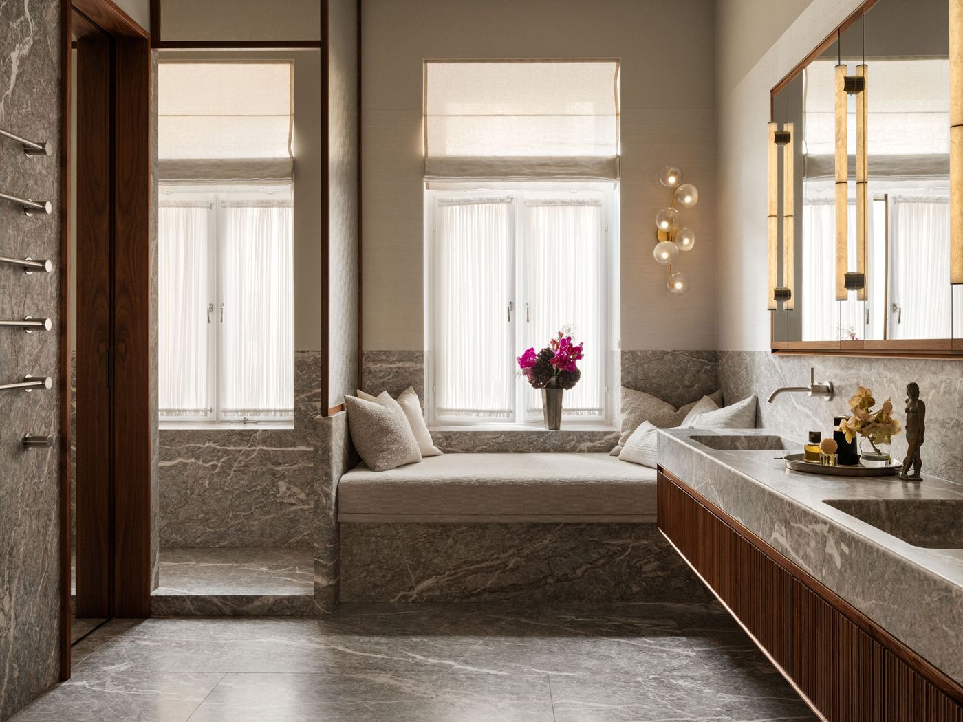 Luxurious bathroom featuring marble accents, a cozy window seat, stylish lighting, and elegant decor with flowers and sculptures. Luxurious bathroom featuring marble accents, a cozy window seat, stylish lighting, and elegant decor with flowers and sculptures.