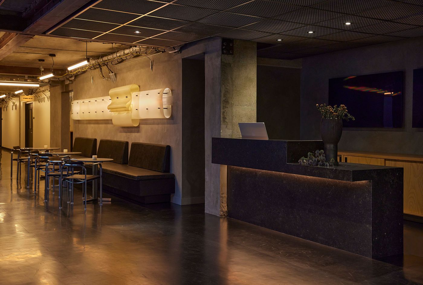 Modern lobby featuring sleek black furnishings, ambient lighting, and a stylish reception desk with floral decor. Modern lobby featuring sleek black furnishings, ambient lighting, and a stylish reception desk with floral decor.