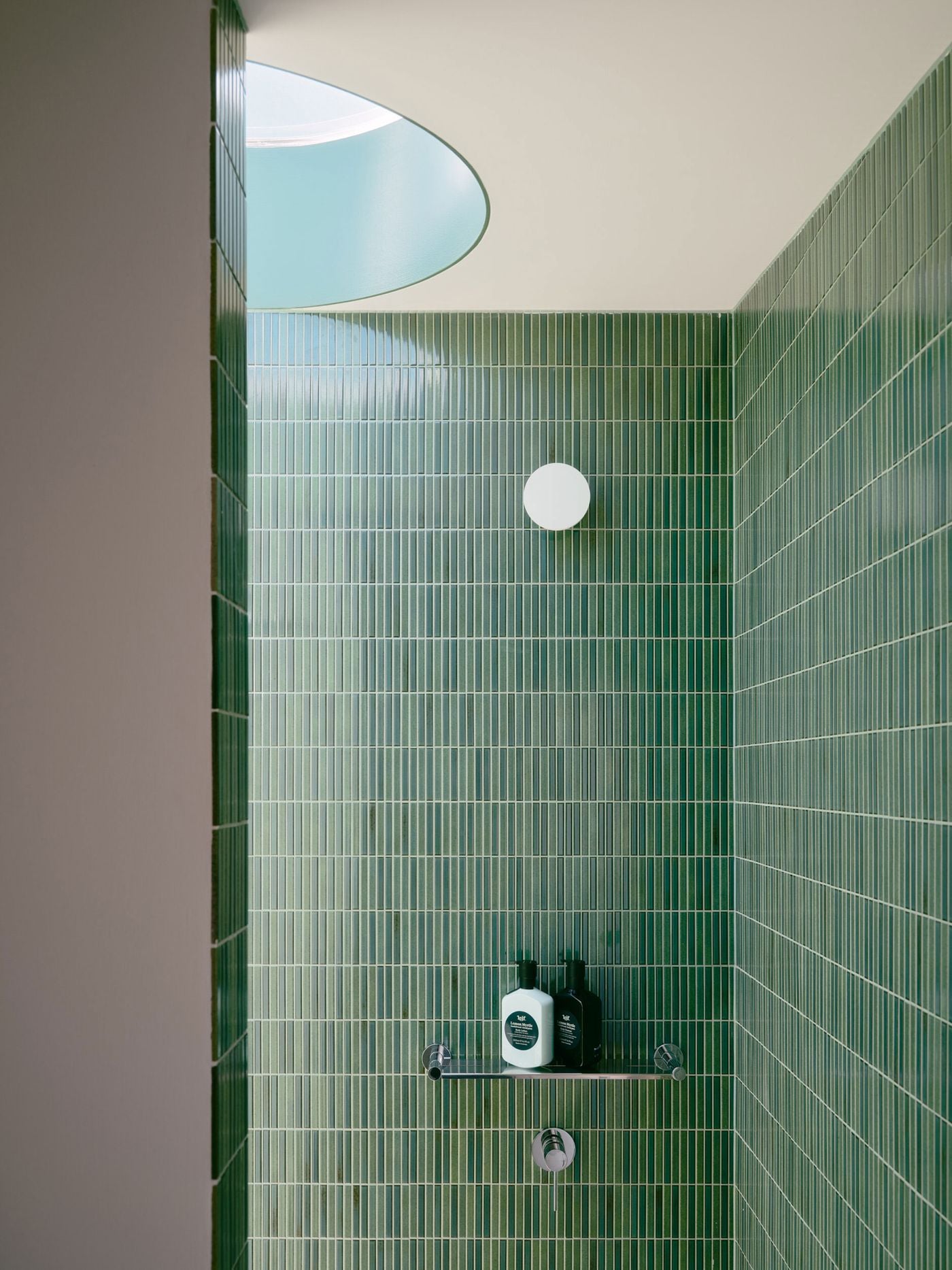 Slender vertically laid green tiles wrap the compact shower enclosure from floor to ceiling, giving the bathroom a rich, immersive quality. Above, a circular skylight introduces diffuse daylight, while a simple globe wall light and pared-back chrome fittings emphasise the clarity of Carter Williamson Architects’ geometric composition. Slender vertically laid green tiles wrap the compact shower enclosure from floor to ceiling, giving the bathroom a rich, immersive quality. Above, a circular skylight introduces diffuse daylight, while a simple globe wall light and pared-back chrome fittings emphasise the clarity of Carter Williamson Architects’ geometric composition.