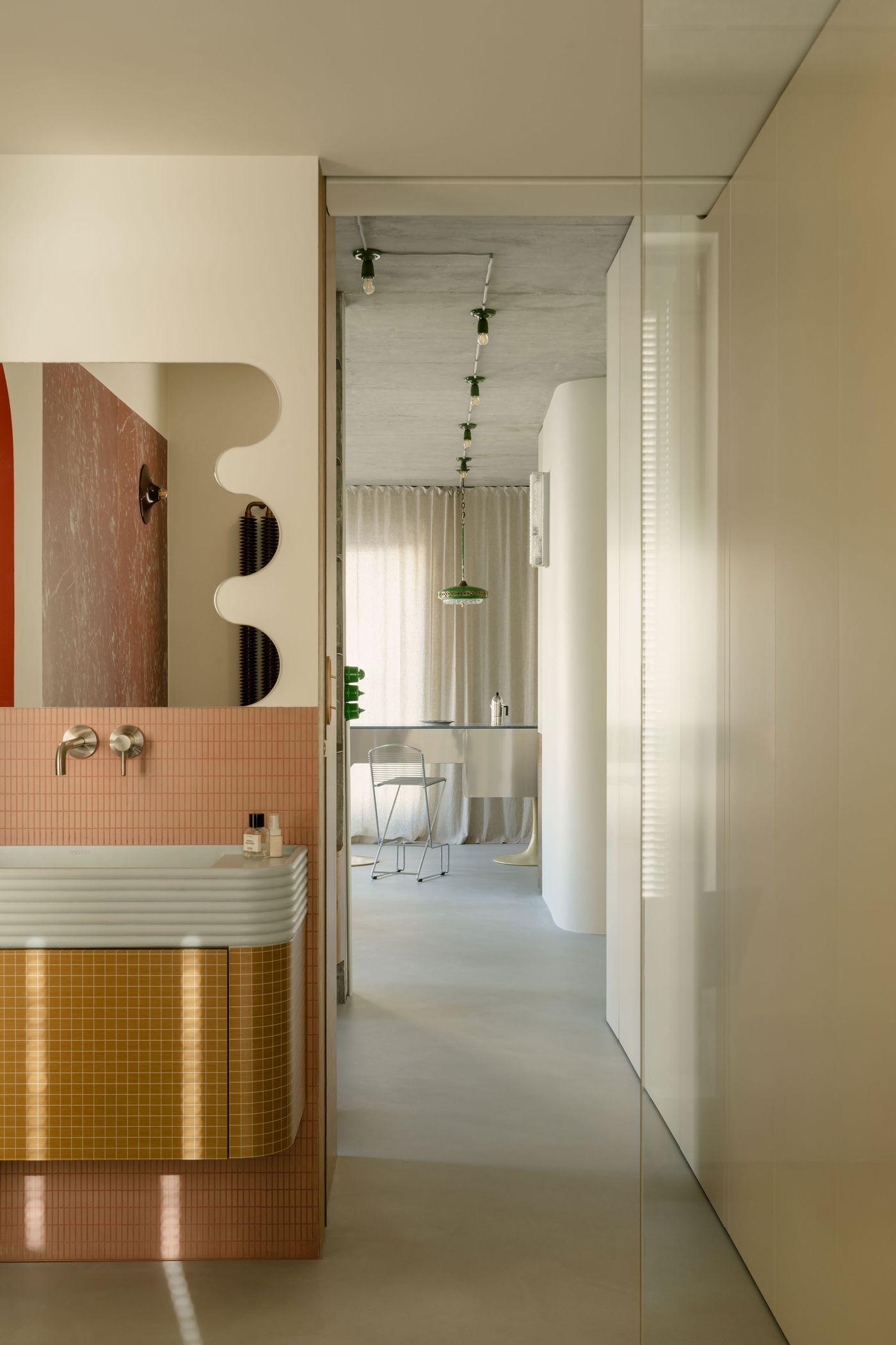 Looking from the hallway toward the kitchen, this transitional view reveals fluid curves, a sculptural basin clad in ochre and rose tiles, and the repeating geometry of the custom dining island beyond. Looking from the hallway toward the kitchen, this transitional view reveals fluid curves, a sculptural basin clad in ochre and rose tiles, and the repeating geometry of the custom dining island beyond.