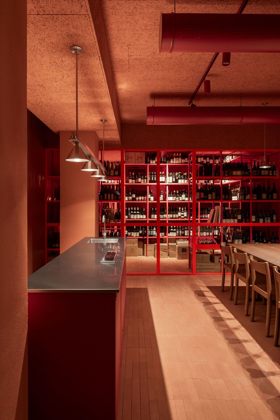 A captivating view of Santo Palato's wine storage area by Naessi Studio, dominated by a striking red metal shelving unit filled with wine bottles, creating a dramatic focal point. A sleek red bar counter with a stainless steel top extends into the foreground. The warm terracotta ceiling and flooring enhance the rich, immersive atmosphere. A captivating view of Santo Palato's wine storage area by Naessi Studio, dominated by a striking red metal shelving unit filled with wine bottles, creating a dramatic focal point. A sleek red bar counter with a stainless steel top extends into the foreground. The warm terracotta ceiling and flooring enhance the rich, immersive atmosphere.