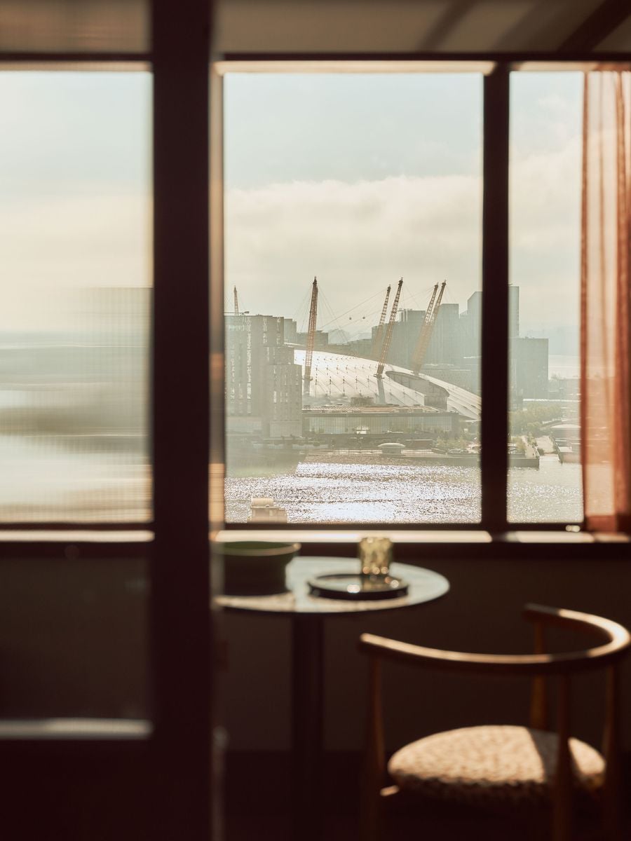 Sunlight pours through the guest-room windows towards the Thames and Greenwich Peninsula, framing the O2’s distinctive roofline and cranes beyond. The view is filtered by dark walnut framing and reeded glass, turning London’s waterside skyline into part of Holloway Li’s carefully composed interior. Sunlight pours through the guest-room windows towards the Thames and Greenwich Peninsula, framing the O2’s distinctive roofline and cranes beyond. The view is filtered by dark walnut framing and reeded glass, turning London’s waterside skyline into part of Holloway Li’s carefully composed interior.