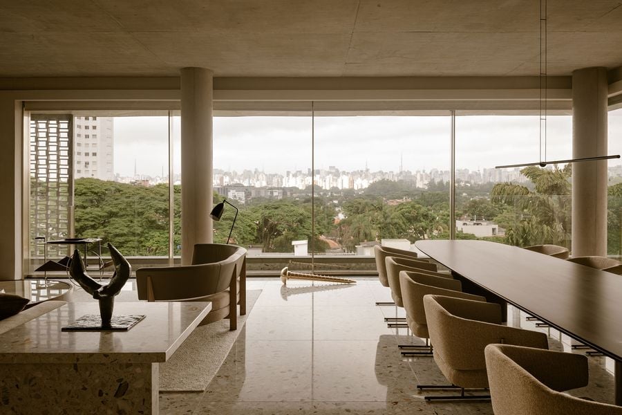 A spacious, modern interior features a dining area and stylish furniture, with a panoramic city view through large windows.