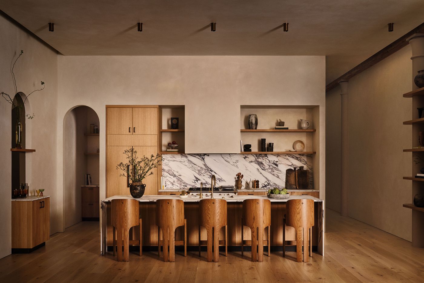 Minimalist kitchen featuring a marble backsplash, wooden cabinets, and tall stools, accented by decorative shelves and natural decor. Minimalist kitchen featuring a marble backsplash, wooden cabinets, and tall stools, accented by decorative shelves and natural decor.