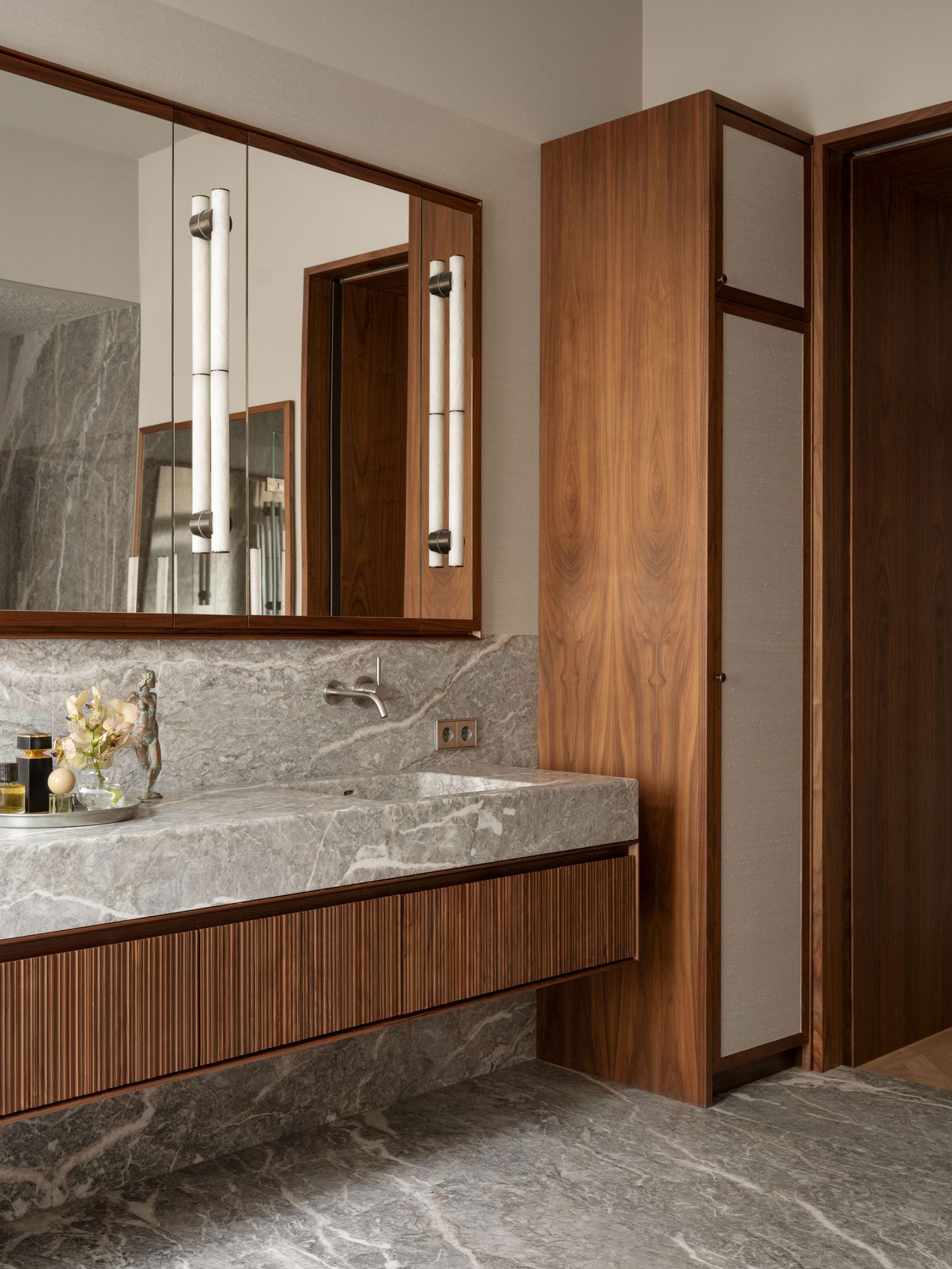 Modern bathroom with marble countertops, wooden cabinetry, and sleek lighting, featuring a spacious mirror above the sink.