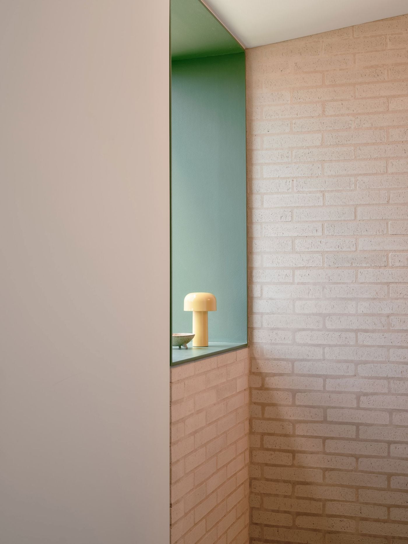 A quiet stairwell detail brings together several recurring materials and colours: pale exposed brick, crisp white walls and a deep sage-green recess. A small yellow mushroom-shaped lamp glows from the niche, turning a functional circulation space into a carefully composed moment of colour, texture and soft ambient light. A quiet stairwell detail brings together several recurring materials and colours: pale exposed brick, crisp white walls and a deep sage-green recess. A small yellow mushroom-shaped lamp glows from the niche, turning a functional circulation space into a carefully composed moment of colour, texture and soft ambient light.