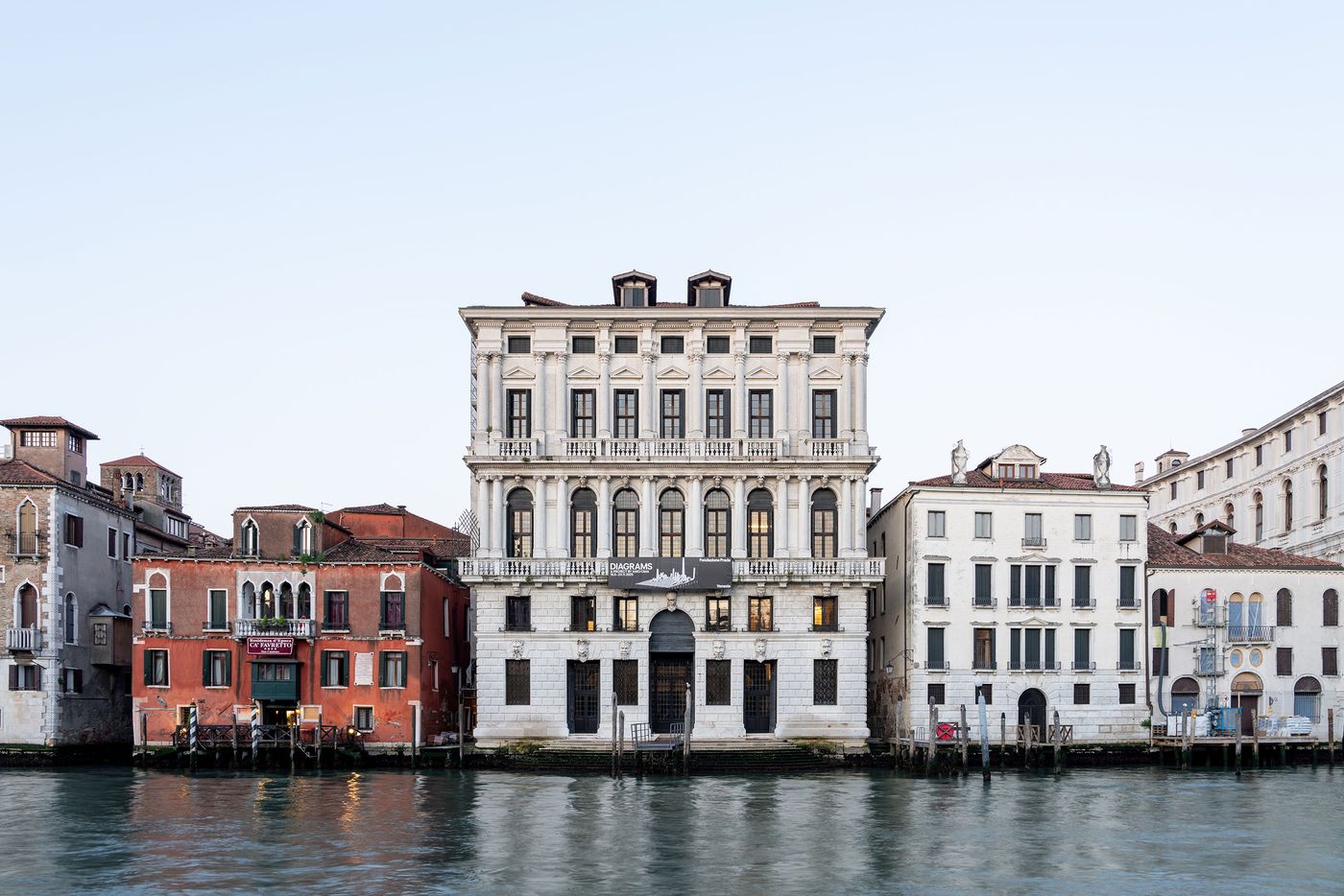 A view of historic Venetian buildings along a canal, featuring prominent white architecture and colorful façades in soft morning light. A view of historic Venetian buildings along a canal, featuring prominent white architecture and colorful façades in soft morning light.