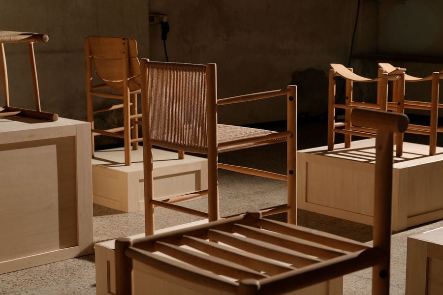 A collection of wooden chairs in a minimalist setting, with natural light casting soft shadows on display pedestals.