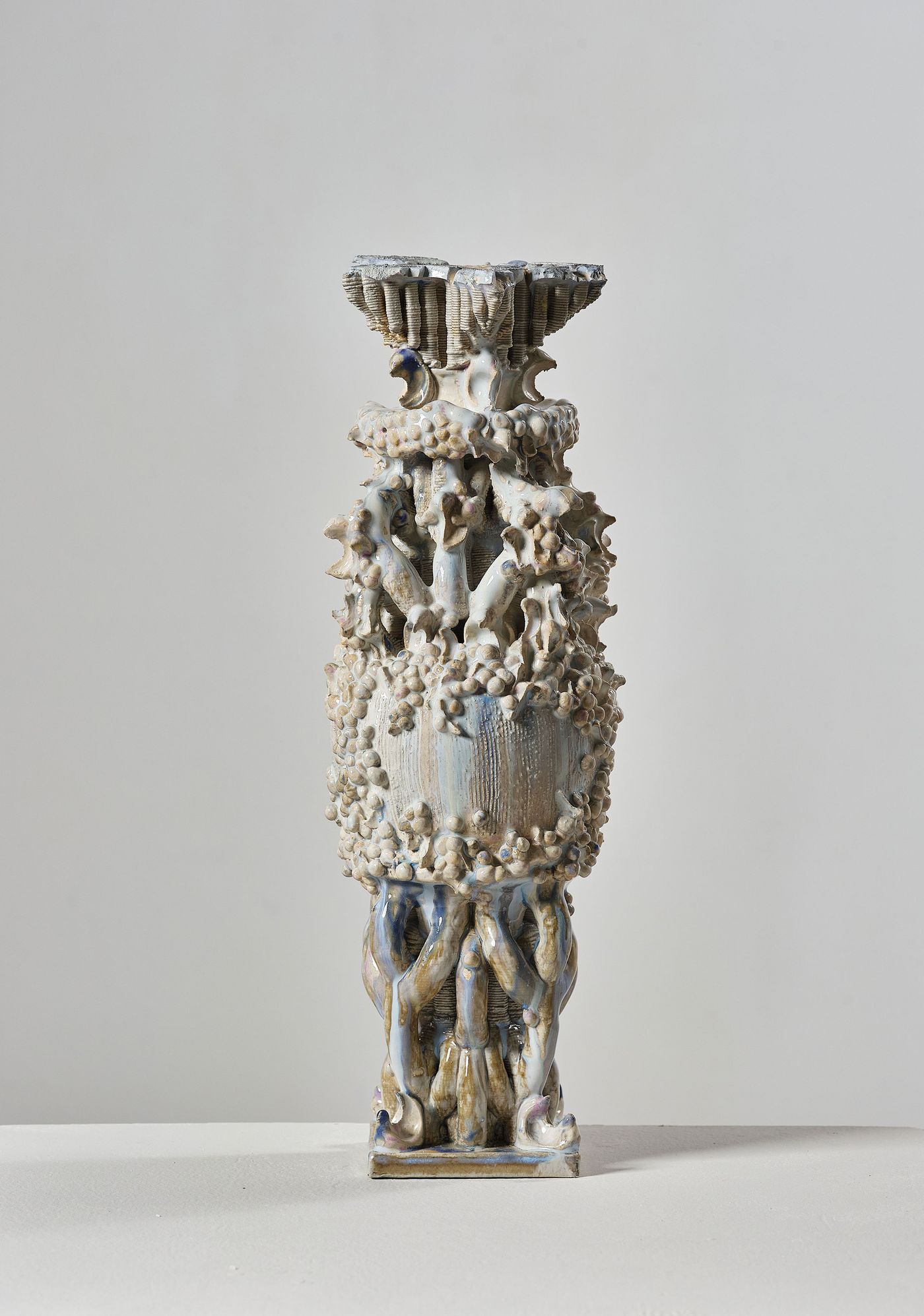 A decorative vase with intricate, organic forms and textures, featuring a mix of glazes in earthy tones against a neutral backdrop. A decorative vase with intricate, organic forms and textures, featuring a mix of glazes in earthy tones against a neutral backdrop.
