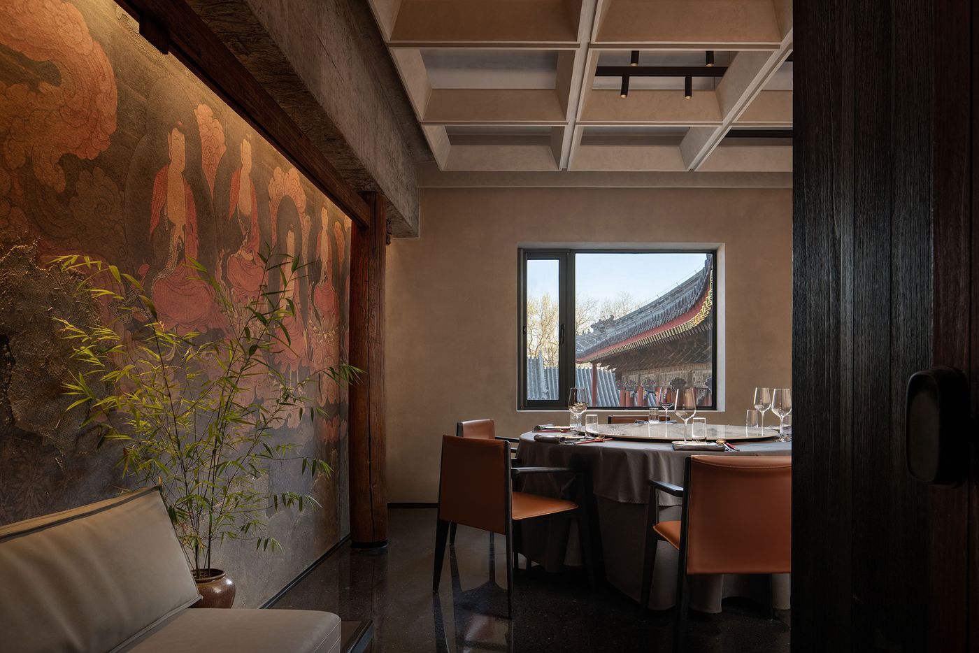 Elegant dining room featuring a mural of serene figures, bamboo plant, and a view of traditional architecture through a window. Elegant dining room featuring a mural of serene figures, bamboo plant, and a view of traditional architecture through a window.
