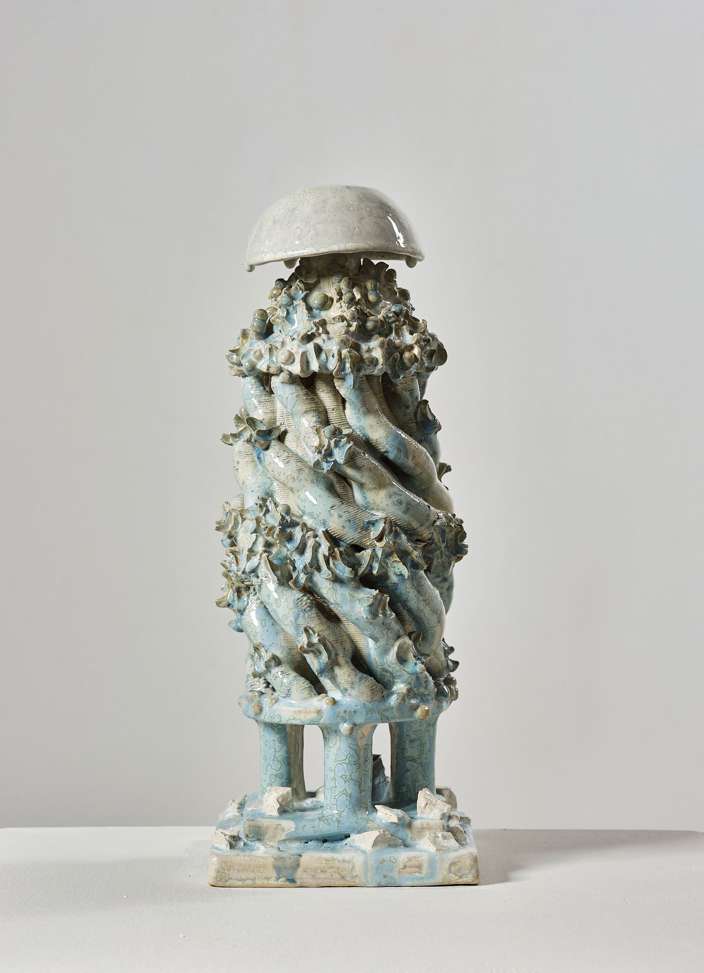 A ceramic sculpture resembling a jellyfish, featuring twisting blue tentacles and a glossy dome atop a textured base. A ceramic sculpture resembling a jellyfish, featuring twisting blue tentacles and a glossy dome atop a textured base.