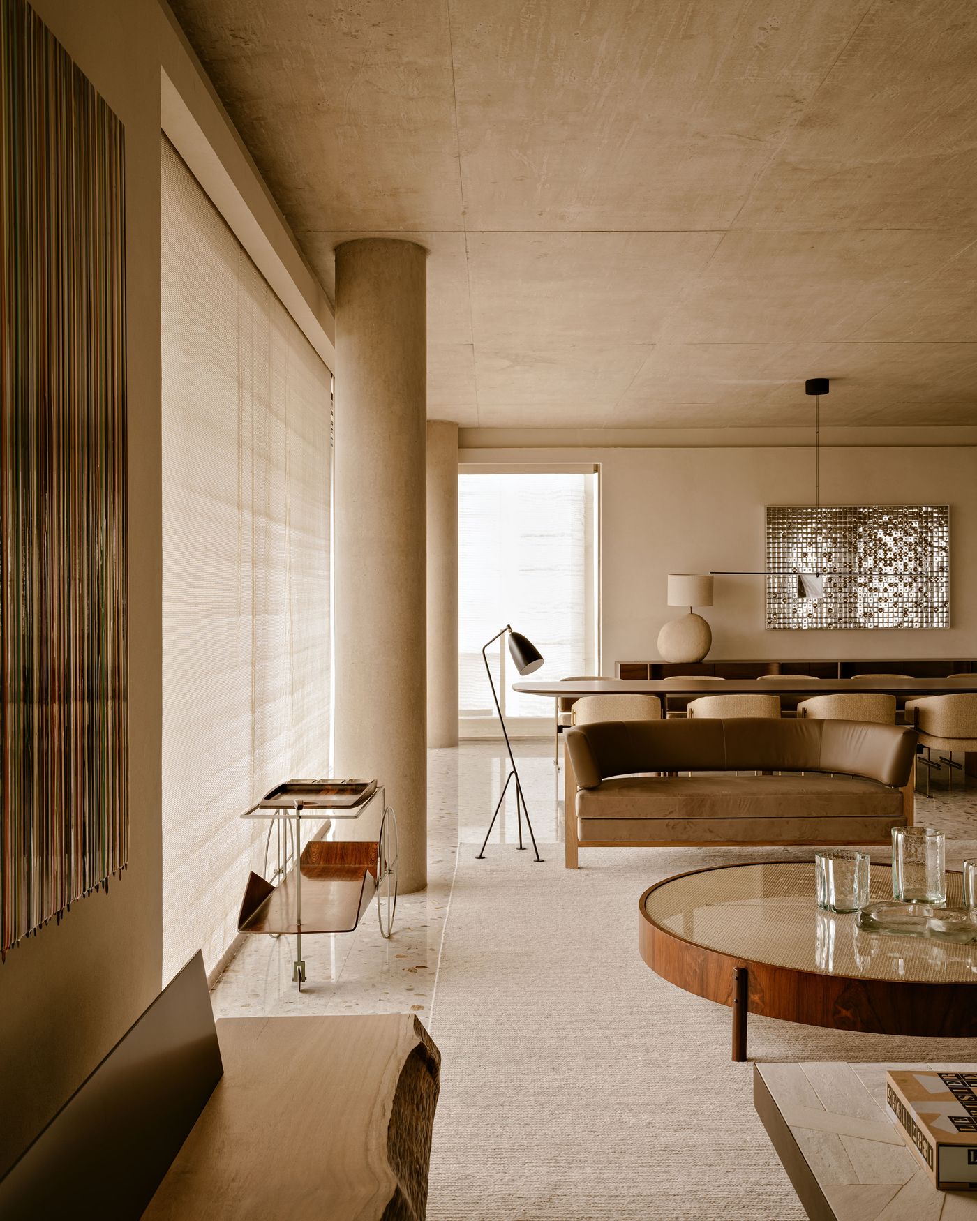 A stylish living room with earthy tones, featuring a modern sofa, circular coffee table, lamp, and textured wall decor. A stylish living room with earthy tones, featuring a modern sofa, circular coffee table, lamp, and textured wall decor.