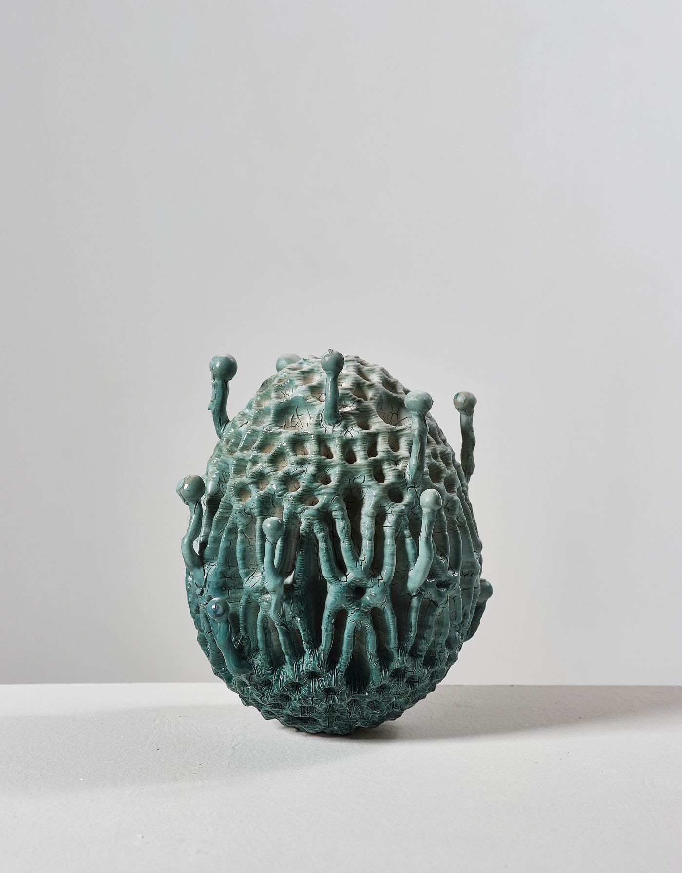An abstract, textured sculpture resembling a vibrant teal egg with protruding shapes and intricate surface details. An abstract, textured sculpture resembling a vibrant teal egg with protruding shapes and intricate surface details.