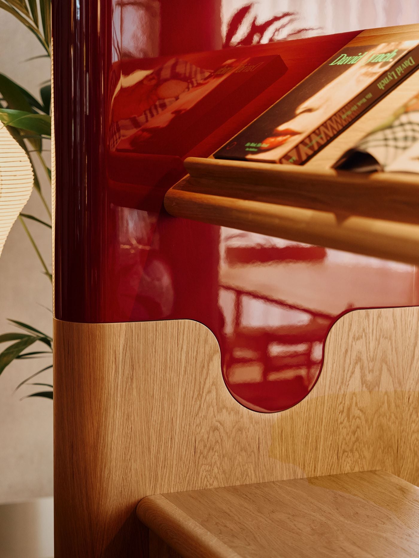 A close-up of the bespoke shelving highlights the contrast between high-gloss burgundy lacquer and rounded oak detailing. The fluid junction between materials, together with the angled magazine ledge, gives the joinery an almost automotive smoothness, reinforcing Holloway Li’s interest in crafted objects that operate as visual characters within the space. A close-up of the bespoke shelving highlights the contrast between high-gloss burgundy lacquer and rounded oak detailing. The fluid junction between materials, together with the angled magazine ledge, gives the joinery an almost automotive smoothness, reinforcing Holloway Li’s interest in crafted objects that operate as visual characters within the space.