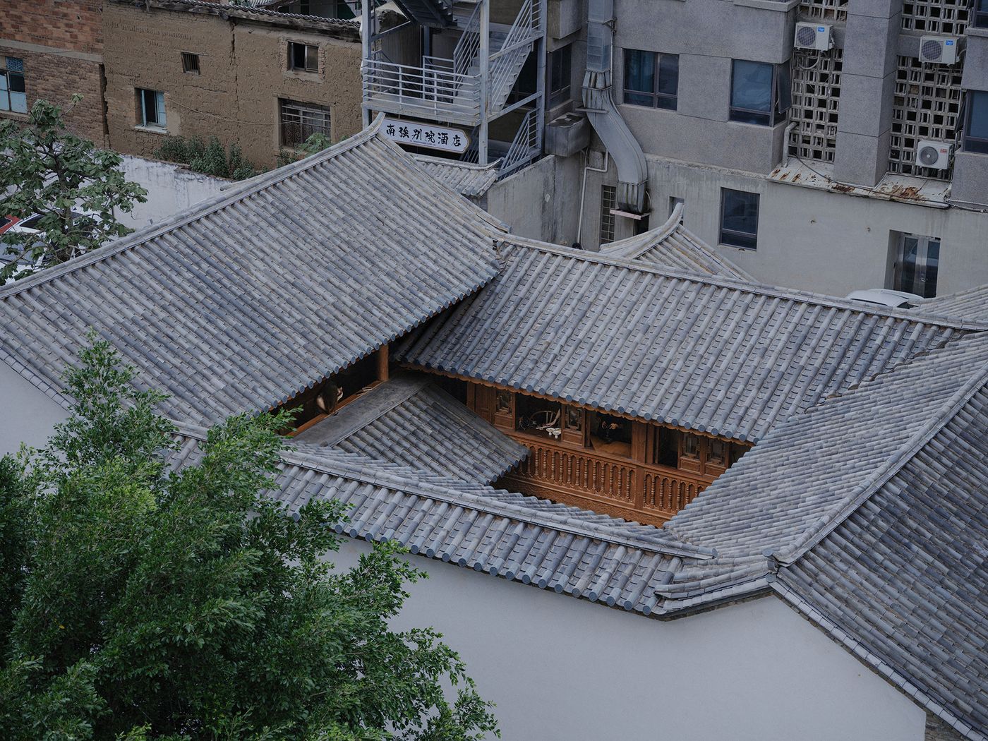Aerial view of traditional Chinese roof with grey tiles, surrounded by modern buildings and greenery, showcasing architectural contrast. Aerial view of traditional Chinese roof with grey tiles, surrounded by modern buildings and greenery, showcasing architectural contrast.