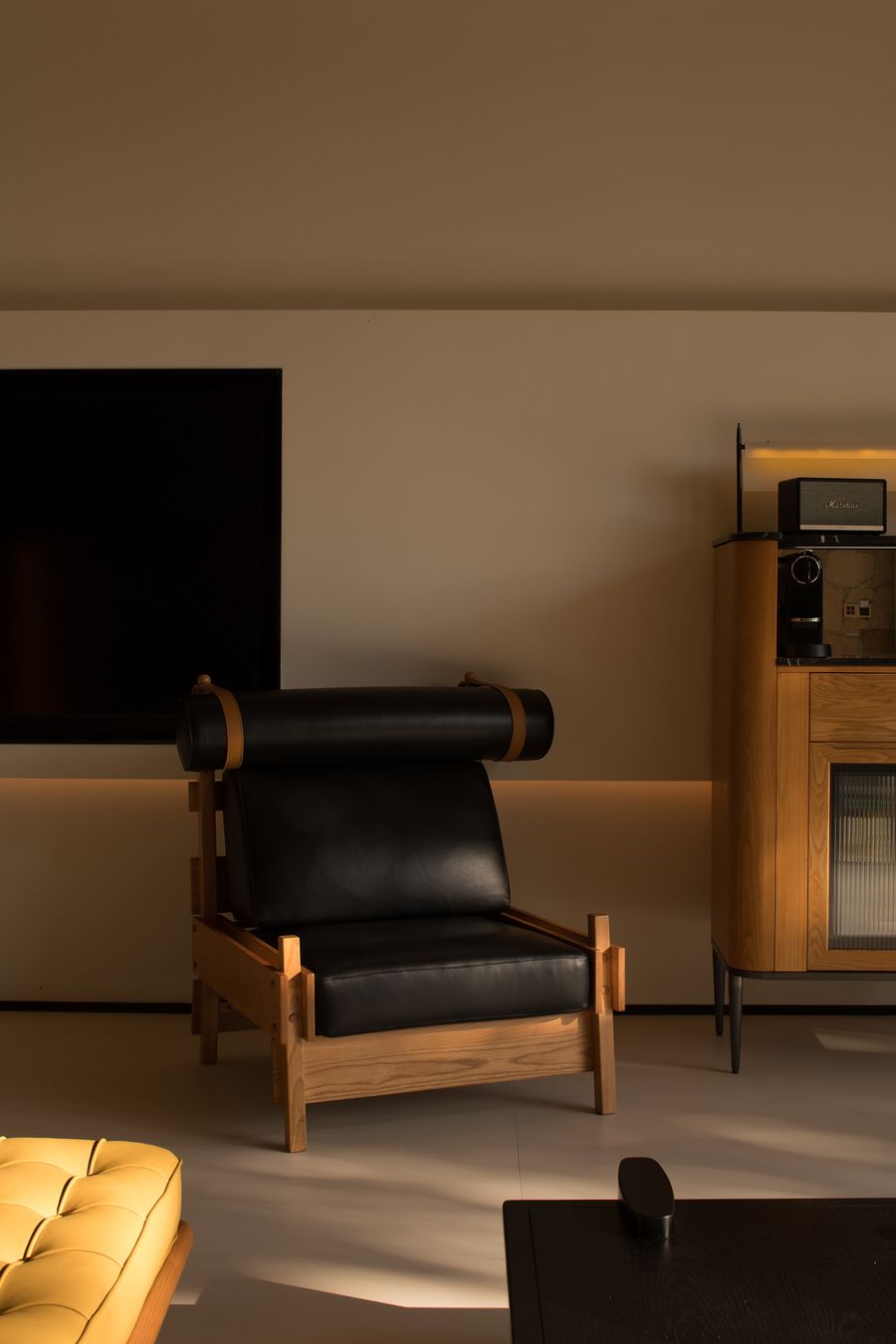 A stylish black leather lounge chair with wooden accents sits beside a sleek television and retro audio unit in a modern living space. A stylish black leather lounge chair with wooden accents sits beside a sleek television and retro audio unit in a modern living space.