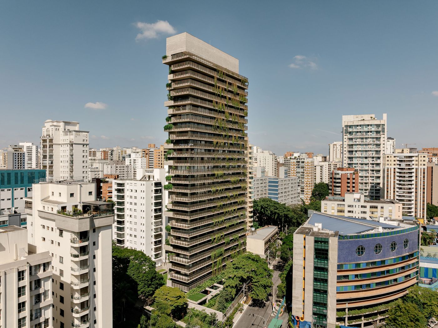 An expansive urban view of São Paulo, featuring the Ibaté tower as a prominent example of biophilic design by Studio Arthur Casas. The building's verdant facade and brutalist concrete form create a striking architectural presence, demonstrating how nature can be woven into high-density living. An expansive urban view of São Paulo, featuring the Ibaté tower as a prominent example of biophilic design by Studio Arthur Casas. The building's verdant facade and brutalist concrete form create a striking architectural presence, demonstrating how nature can be woven into high-density living.