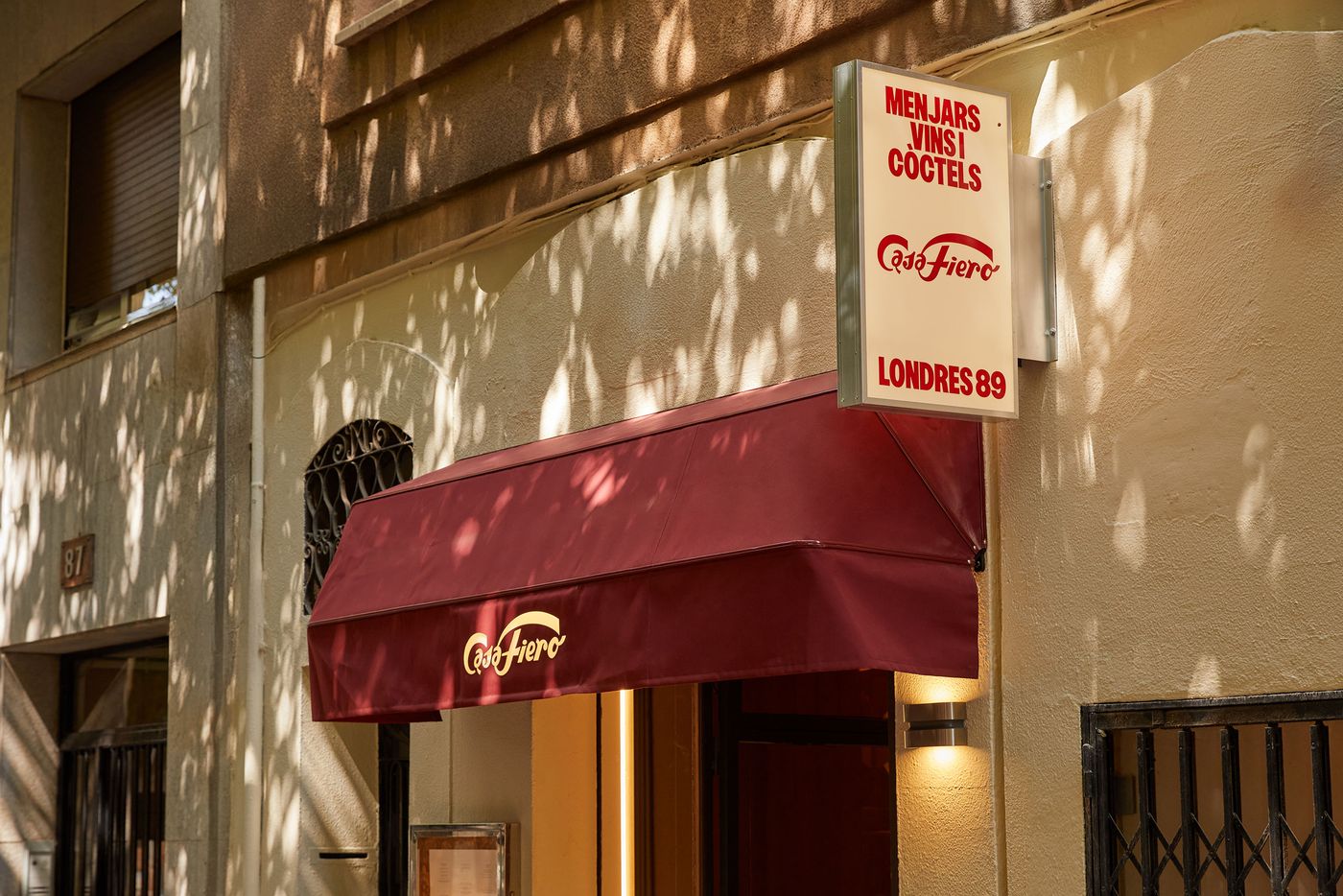 A sun-drenched street view reveals the inviting facade of a restaurant. A bold red awning and a simple, illuminated sign cast playful shadows on the textured, ochre-colored building. The composition captures a welcoming atmosphere and classic Mediterranean charm. A sun-drenched street view reveals the inviting facade of a restaurant. A bold red awning and a simple, illuminated sign cast playful shadows on the textured, ochre-colored building. The composition captures a welcoming atmosphere and classic Mediterranean charm.