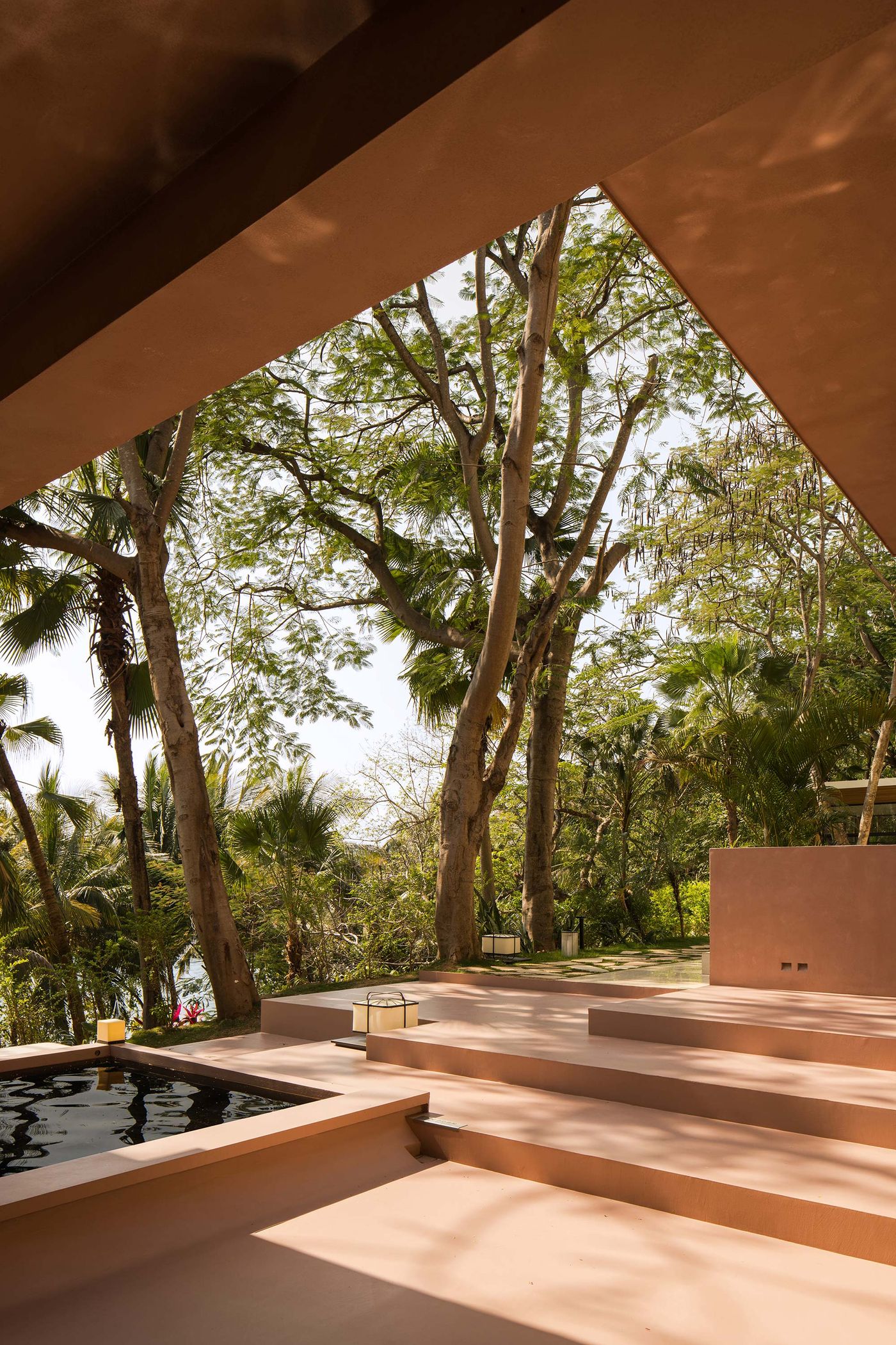 A serene outdoor space with stepped terracotta areas leading to a reflective pool, surrounded by lush greenery and tall trees. A serene outdoor space with stepped terracotta areas leading to a reflective pool, surrounded by lush greenery and tall trees.