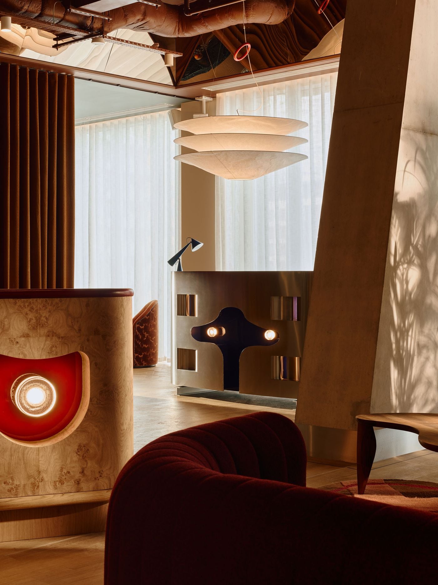 Holloway Li’s cinematic approach comes into focus in this ground-floor vignette, where sculptural joinery, velvet seating and an oversized paper pendant are juxtaposed with exposed concrete and services. In the background, the stainless-steel DJ booth glows like a retro-futuristic machine, its illuminated details recalling 1960s automotive design. Holloway Li’s cinematic approach comes into focus in this ground-floor vignette, where sculptural joinery, velvet seating and an oversized paper pendant are juxtaposed with exposed concrete and services. In the background, the stainless-steel DJ booth glows like a retro-futuristic machine, its illuminated details recalling 1960s automotive design.