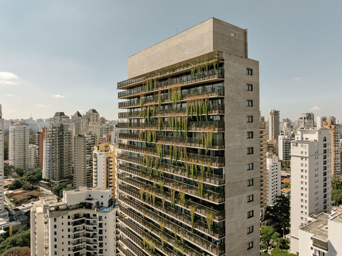 An elevated perspective of the Ibaté tower, revealing its majestic presence within the São Paulo cityscape. The building's concrete form is softened by widespread vertical greenery, emphasizing its role as a biophilic landmark that merges architectural strength with natural beauty. An elevated perspective of the Ibaté tower, revealing its majestic presence within the São Paulo cityscape. The building's concrete form is softened by widespread vertical greenery, emphasizing its role as a biophilic landmark that merges architectural strength with natural beauty.