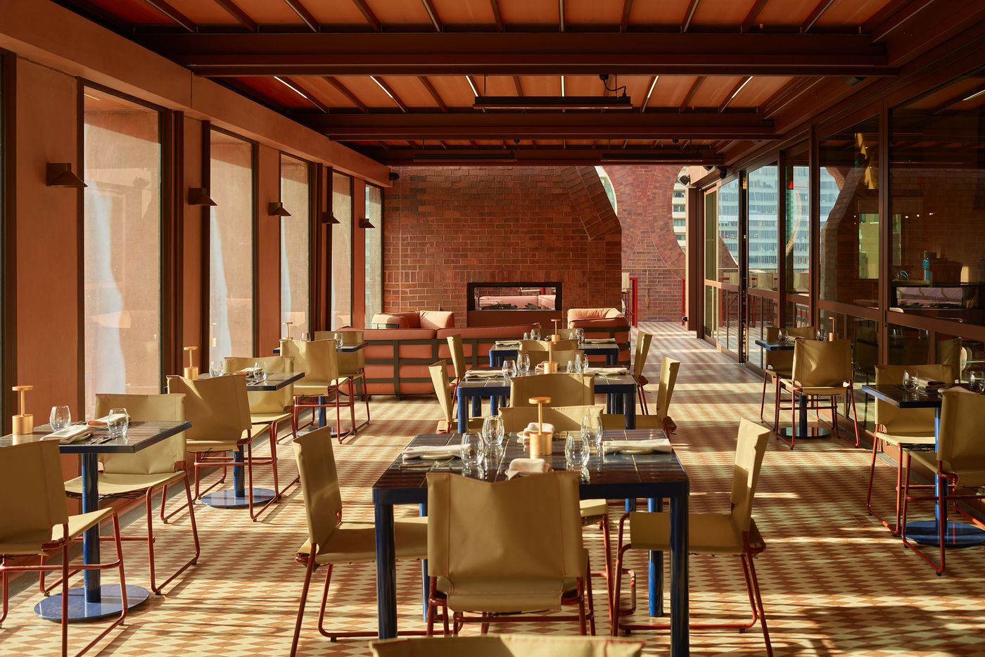 A stylish restaurant interior with wooden beams, glass walls, and neatly arranged tables with beige chairs, creating a warm ambiance. A stylish restaurant interior with wooden beams, glass walls, and neatly arranged tables with beige chairs, creating a warm ambiance.