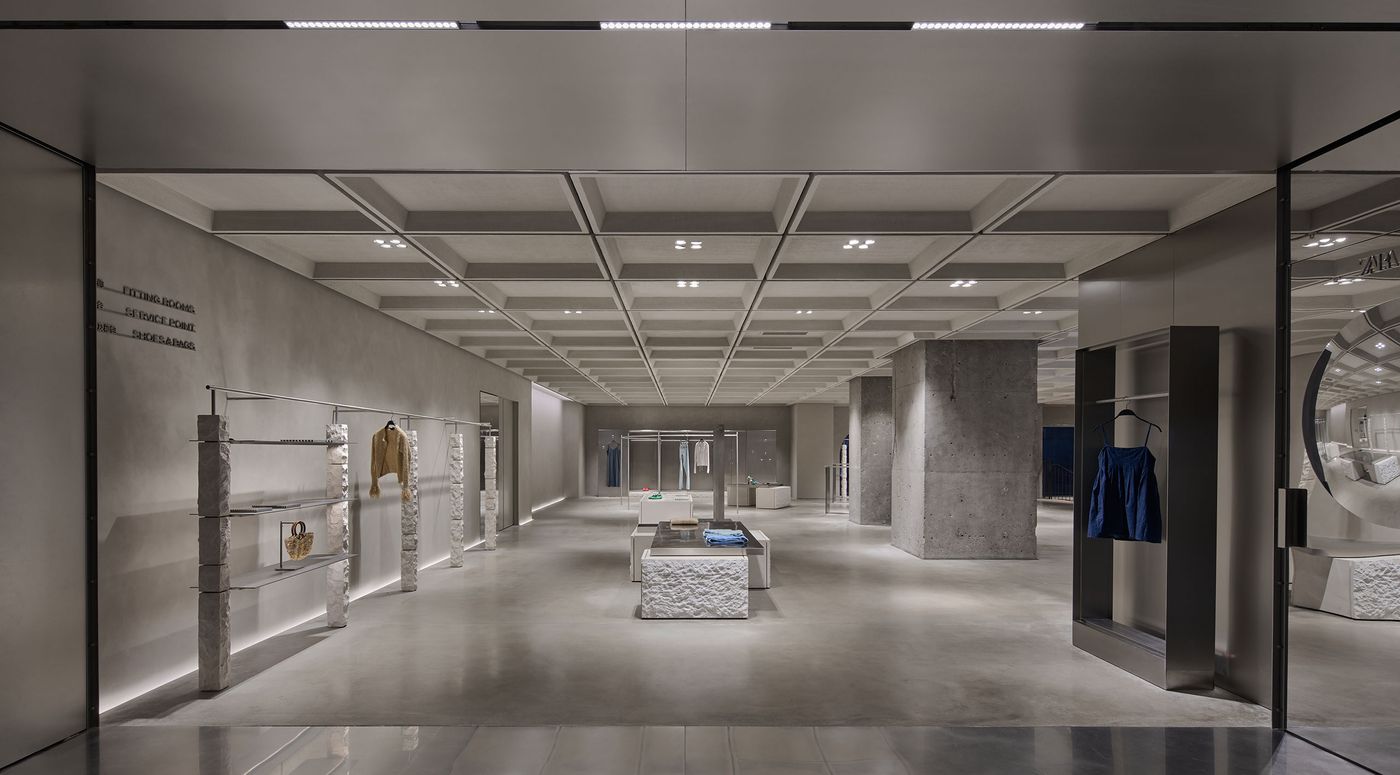 Modern retail space featuring minimalist design, showcasing clothing and accessories on sleek displays and concrete walls. Modern retail space featuring minimalist design, showcasing clothing and accessories on sleek displays and concrete walls.