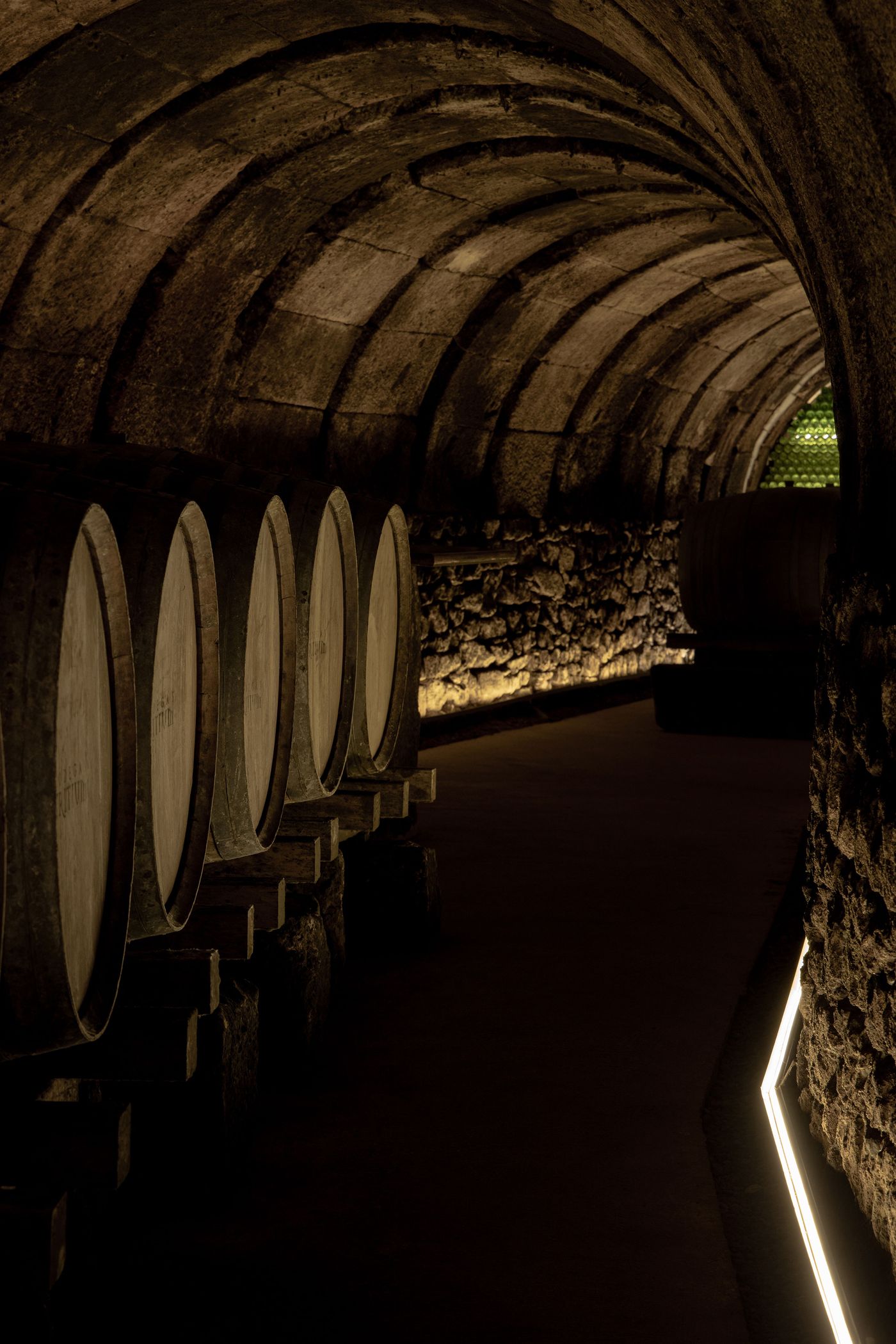Dimly lit wine cellar featuring wooden barrels along stone walls, with soft lighting enhancing the arched ceiling and atmosphere. Dimly lit wine cellar featuring wooden barrels along stone walls, with soft lighting enhancing the arched ceiling and atmosphere.