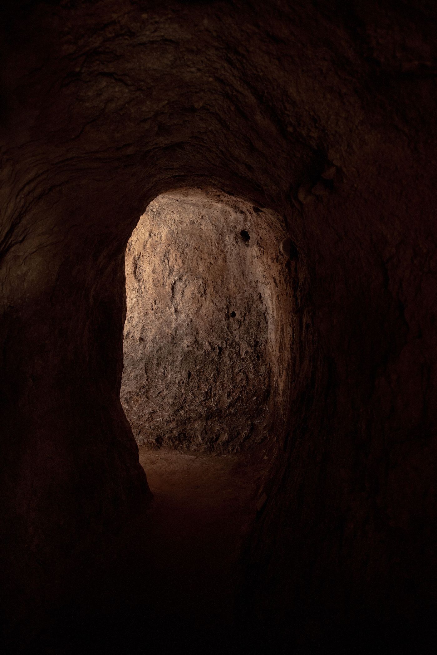A dimly lit tunnel with rough, dark walls, leading to a brighter opening, suggesting depth and a sense of exploration.§§§ A dimly lit tunnel with rough, dark walls, leading to a brighter opening, suggesting depth and a sense of exploration.§§§