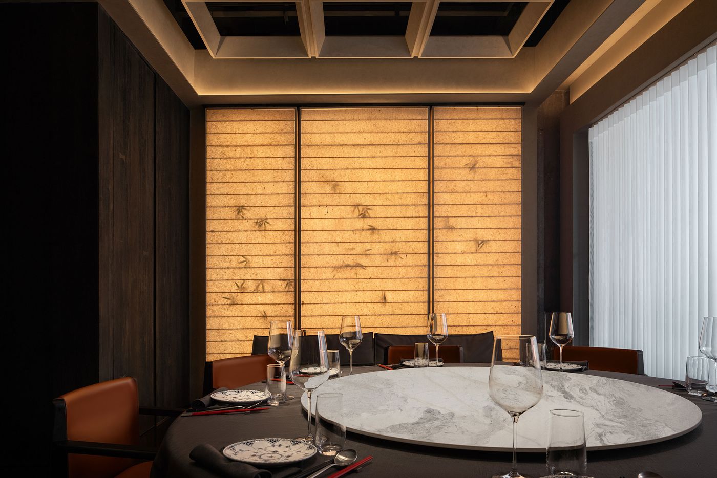 A modern dining room with a round marble table, elegant glassware, and softly lit textured walls, creating an inviting atmosphere. A modern dining room with a round marble table, elegant glassware, and softly lit textured walls, creating an inviting atmosphere.
