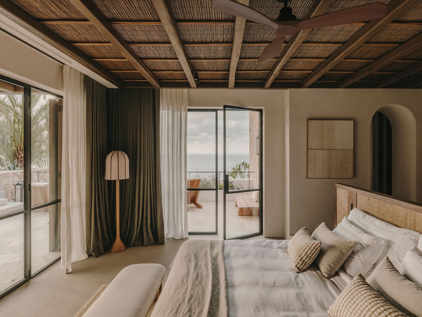 A serene bedroom with a coastal view, featuring a comfortable bed, elegant curtains, and warm wood accents. A serene bedroom with a coastal view, featuring a comfortable bed, elegant curtains, and warm wood accents.