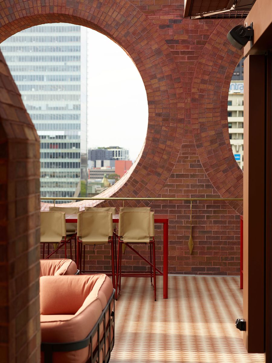A stylish balcony featuring a circular brick arch, modern seating, and a city skyline view beyond. A stylish balcony featuring a circular brick arch, modern seating, and a city skyline view beyond.