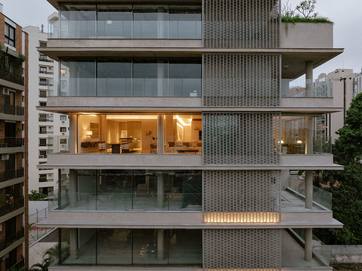 Modern multi-story building with glass balconies and illuminated interior, showcasing minimalist design and urban surroundings. Modern multi-story building with glass balconies and illuminated interior, showcasing minimalist design and urban surroundings.