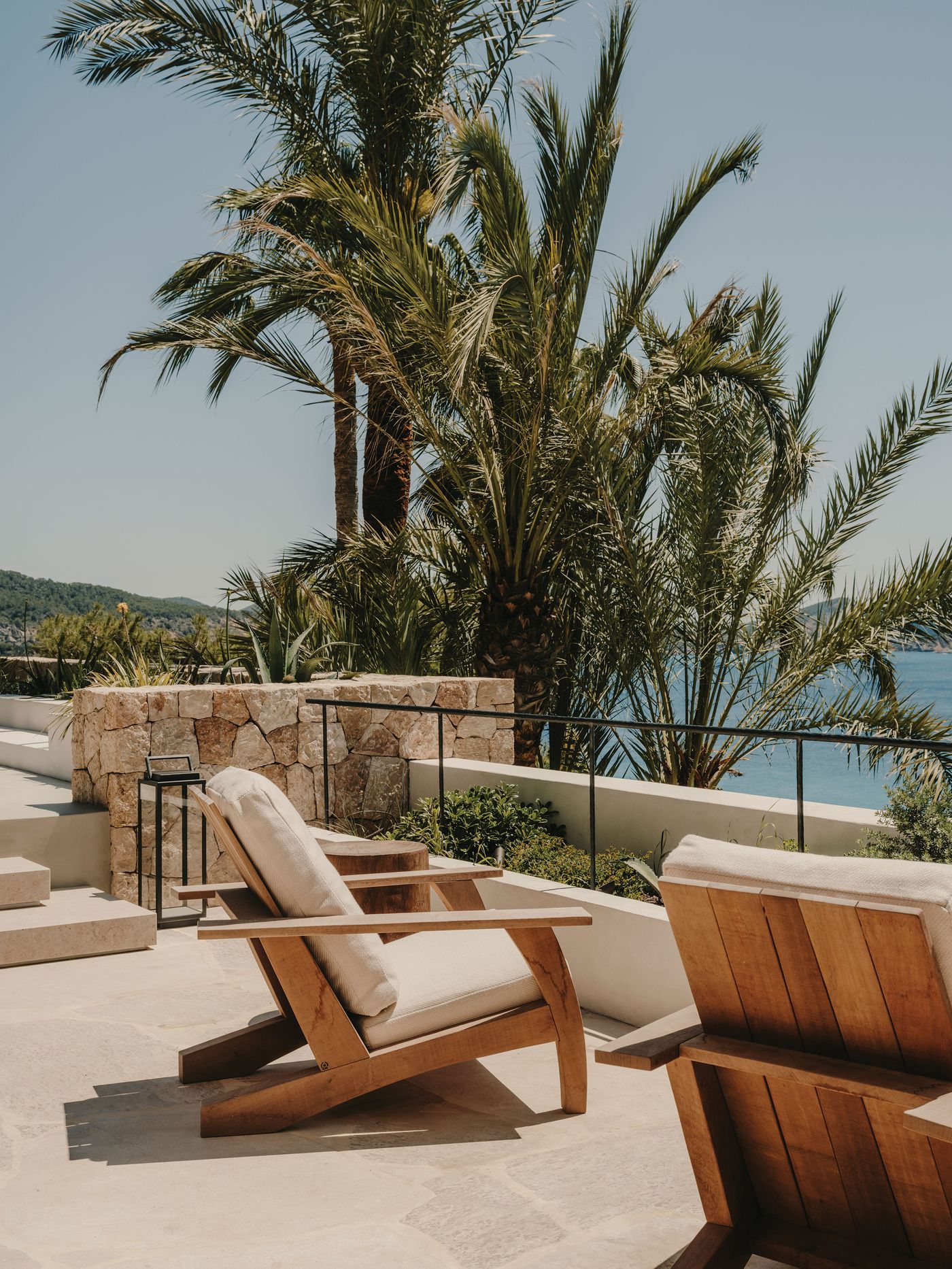 Sun-drenched patio featuring wooden lounges, surrounded by lush palm trees and a view of the serene blue sea. Sun-drenched patio featuring wooden lounges, surrounded by lush palm trees and a view of the serene blue sea.
