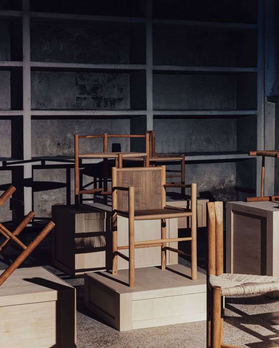 A collection of wooden chairs arranged on light wooden boxes, set against a dark, textured background with soft shadows. A collection of wooden chairs arranged on light wooden boxes, set against a dark, textured background with soft shadows.