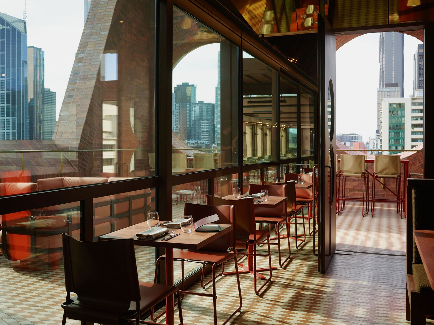 Indoor dining area with modern tables and chairs, featuring large windows with city skyline views, inviting natural light. Indoor dining area with modern tables and chairs, featuring large windows with city skyline views, inviting natural light.