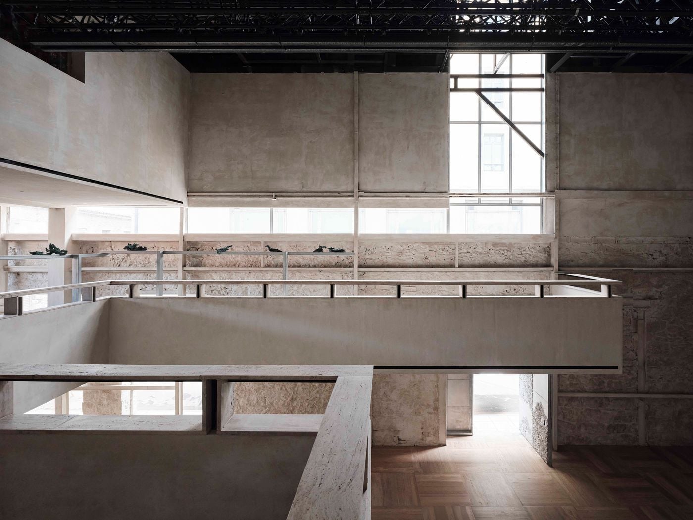 Inside Castor Place, bridges and elevated walkways organise the double-height gallery while preserving expansive sightlines across the space. Pale surfaces and exposed historic masonry are set beneath a black steel roof structure, with large windows washing the layered interior in natural light. Inside Castor Place, bridges and elevated walkways organise the double-height gallery while preserving expansive sightlines across the space. Pale surfaces and exposed historic masonry are set beneath a black steel roof structure, with large windows washing the layered interior in natural light.