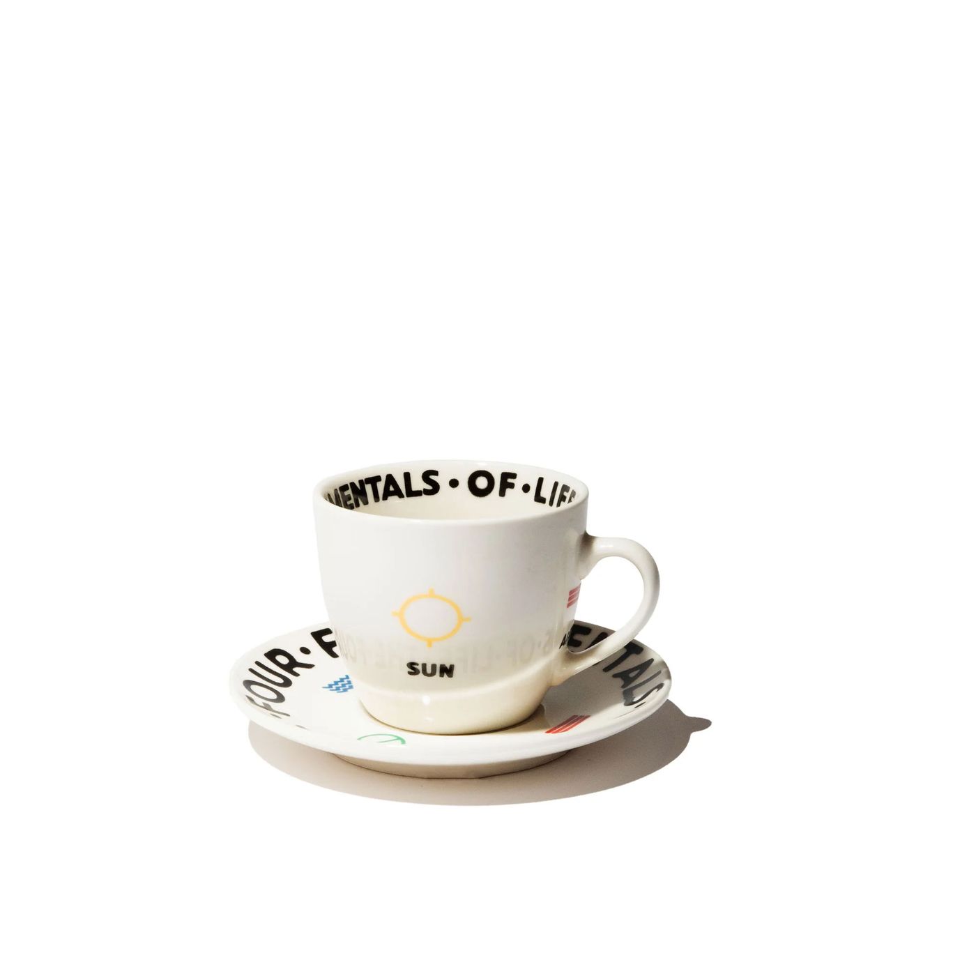 A white ceramic cup with black text and a yellow sun graphic, accompanied by a matching saucer.