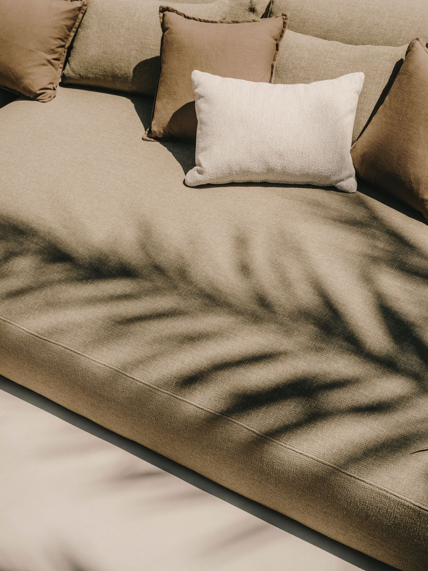 A beige sofa adorned with brown and cream pillows, featuring soft textures and gentle shadows creating a cozy, inviting atmosphere. A beige sofa adorned with brown and cream pillows, featuring soft textures and gentle shadows creating a cozy, inviting atmosphere.