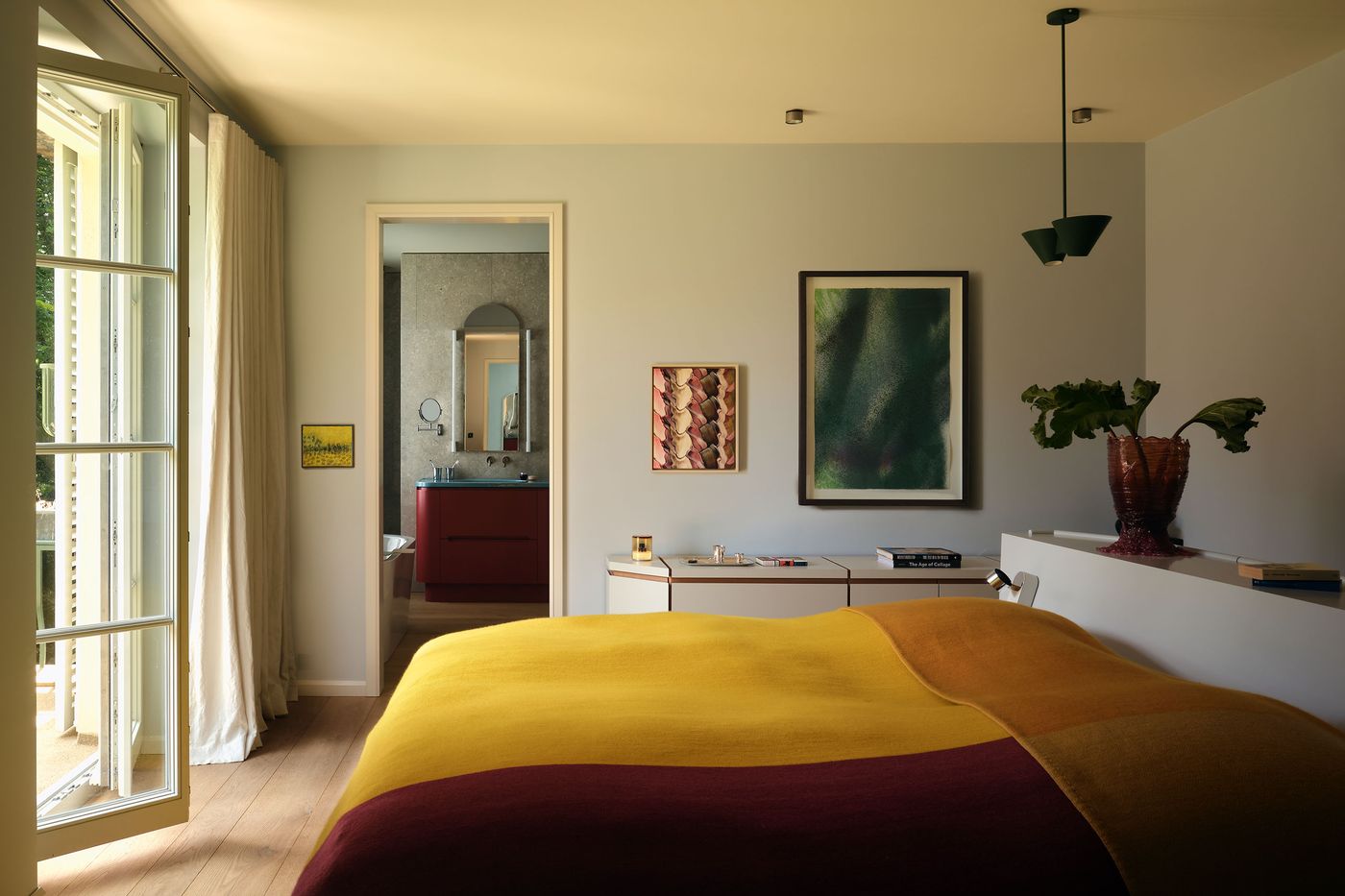 Bright bedroom featuring a cozy yellow and brown blanket, stylish decor, and an open door leading to a modern bathroom. Bright bedroom featuring a cozy yellow and brown blanket, stylish decor, and an open door leading to a modern bathroom.
