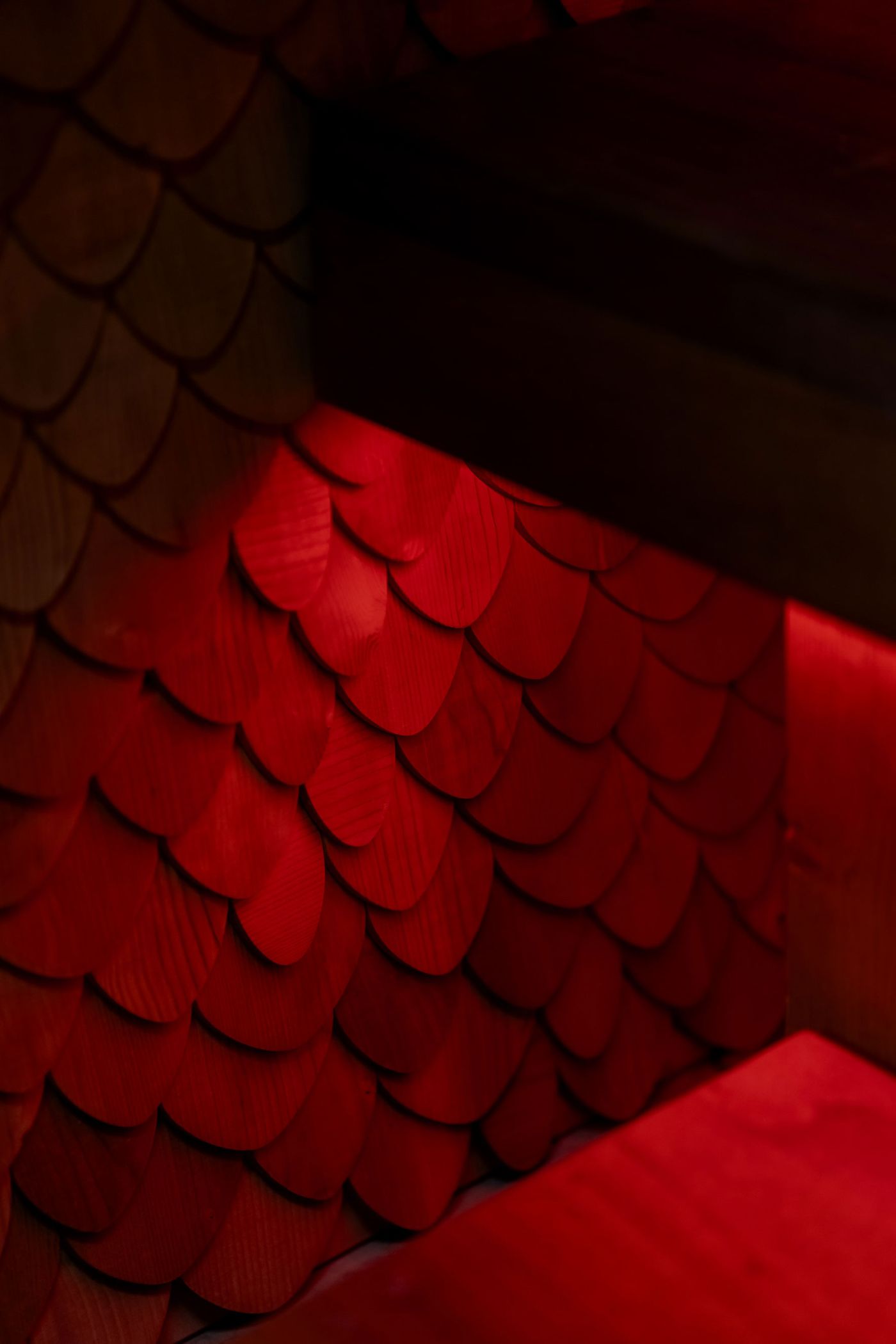 Close-up of textured wooden scales in vibrant red, illuminated softly by ambient light, creating a cozy, dramatic effect.