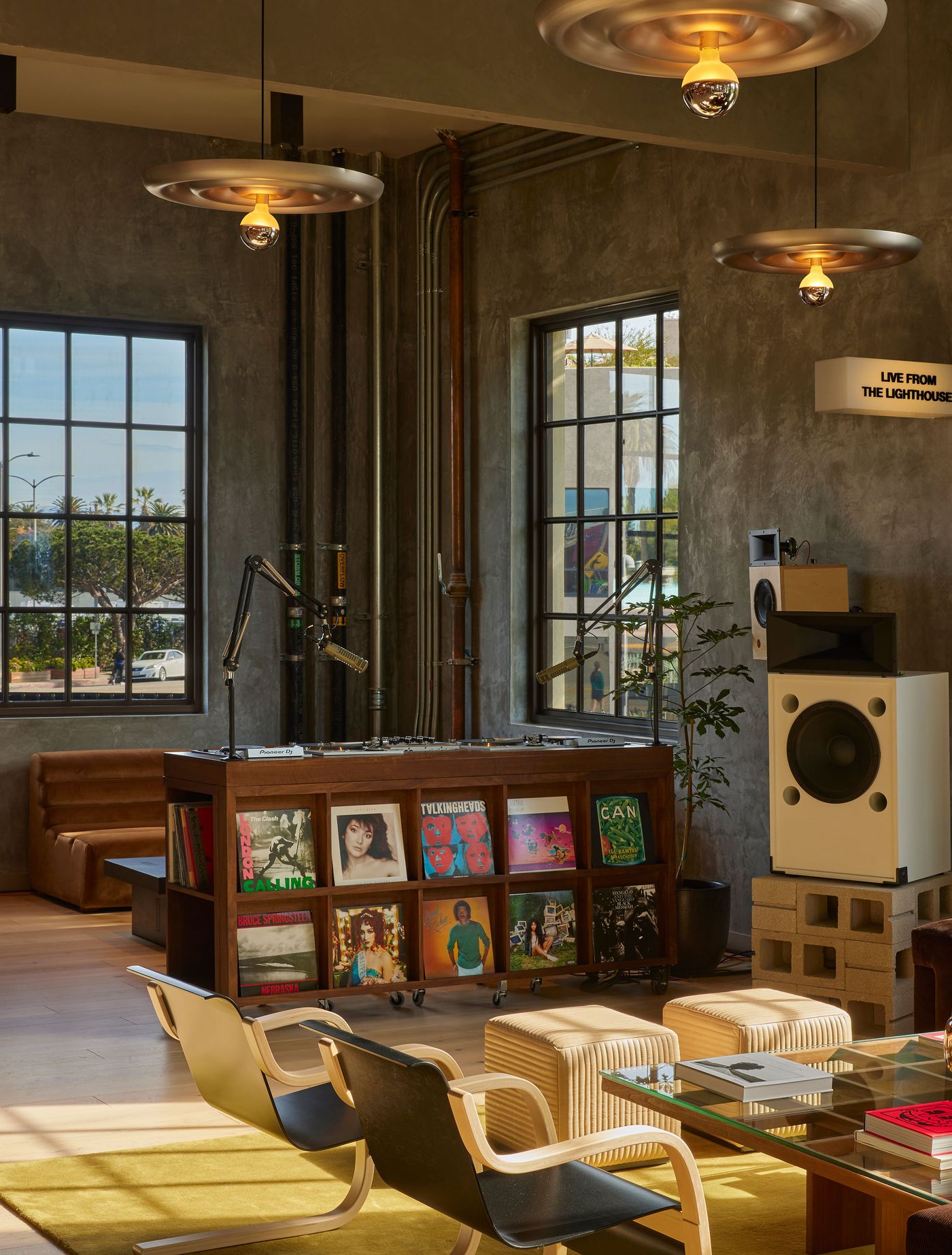 A stylish interior featuring a record player setup, cozy seating, and large windows, infused with natural light and creative decor. A stylish interior featuring a record player setup, cozy seating, and large windows, infused with natural light and creative decor.