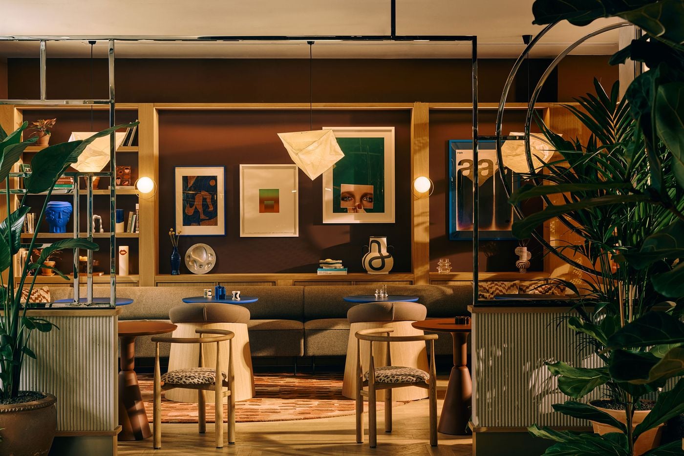 Chrome framing gives the library café a stage-like presence within Locke London Canary Wharf’s ground floor. Earthy brown walls and pale timber are punctuated by ultramarine tables, artwork and decorative objects, while dense planting and geometric lighting reinforce Holloway Li’s layered, film-set-inspired approach to the communal interiors. Chrome framing gives the library café a stage-like presence within Locke London Canary Wharf’s ground floor. Earthy brown walls and pale timber are punctuated by ultramarine tables, artwork and decorative objects, while dense planting and geometric lighting reinforce Holloway Li’s layered, film-set-inspired approach to the communal interiors.