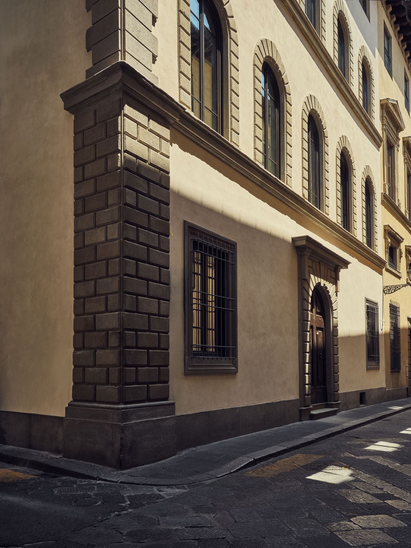 Slanting sunlight crosses the restored facade of La Réserve Firenze, where rusticated stone quoins anchor the corner of the palazzo. Arched upper windows set in stone surrounds, barred ground-floor openings and a pedimented portal articulate the ochre render in the classic language of Florentine Renaissance architecture. Slanting sunlight crosses the restored facade of La Réserve Firenze, where rusticated stone quoins anchor the corner of the palazzo. Arched upper windows set in stone surrounds, barred ground-floor openings and a pedimented portal articulate the ochre render in the classic language of Florentine Renaissance architecture.