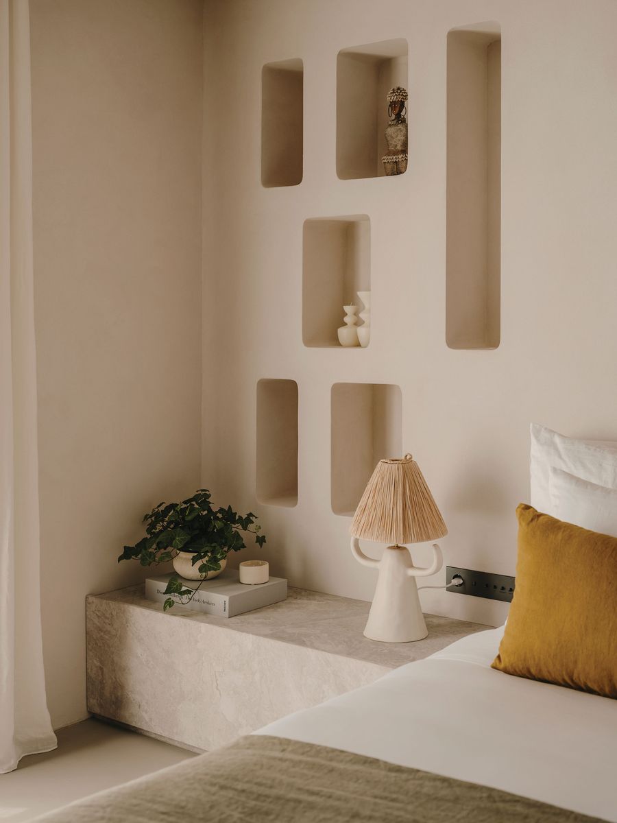 A cozy bedroom featuring a minimalist design with a textured wall, decorative niches, a potted plant, and a unique lamp. A cozy bedroom featuring a minimalist design with a textured wall, decorative niches, a potted plant, and a unique lamp.