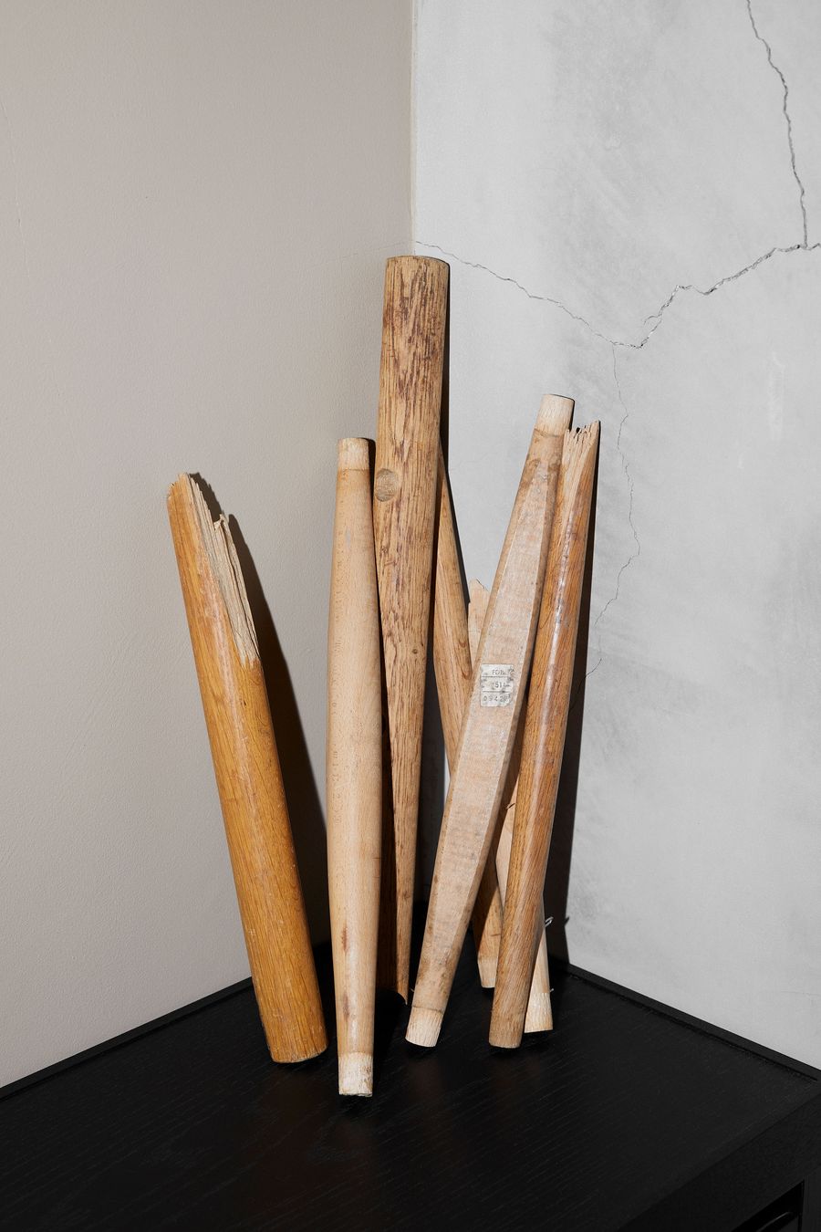 A collection of various wooden sticks in different lengths and textures, leaning against a wall with a cracked finish. A collection of various wooden sticks in different lengths and textures, leaning against a wall with a cracked finish.
