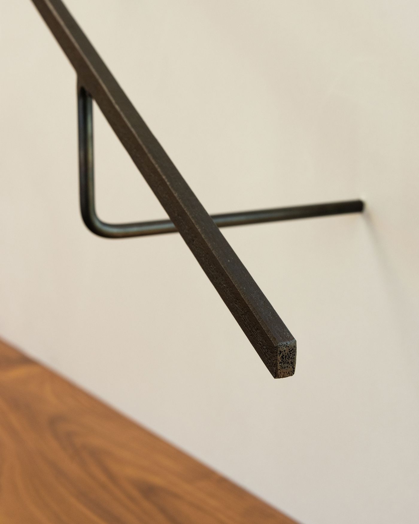 Close-up of a black metal bracket mounted on a wall, showcasing its angular design against a wooden surface.