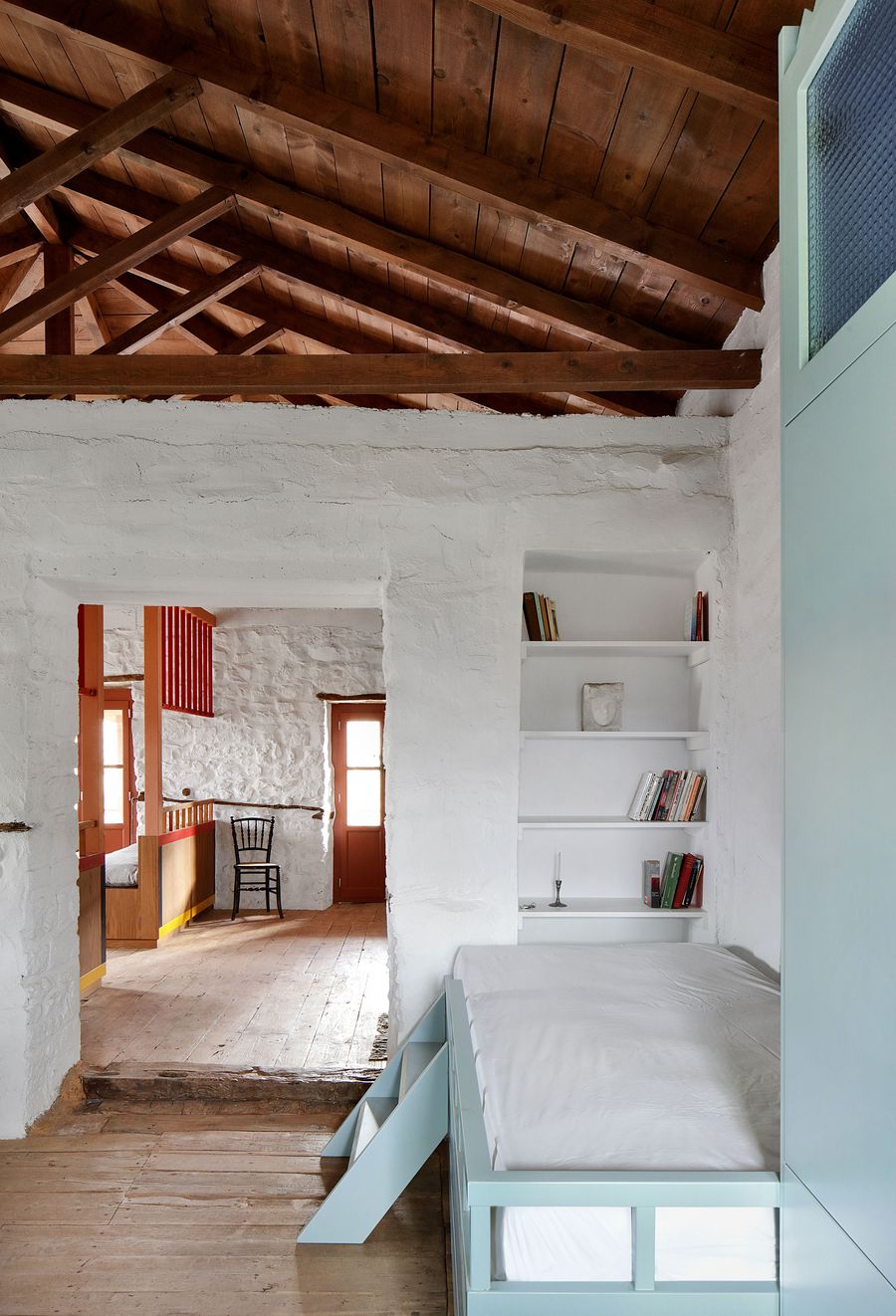 Multi-level sleeping alcove showcases the project's sophisticated approach to spatial organization, where sage-green built-ins create intimate zones beneath the exposed timber roof structure. The composition reveals layers of architectural intervention, demonstrating how contemporary elements can enhance traditional Mediterranean spaces while maintaining authentic character.