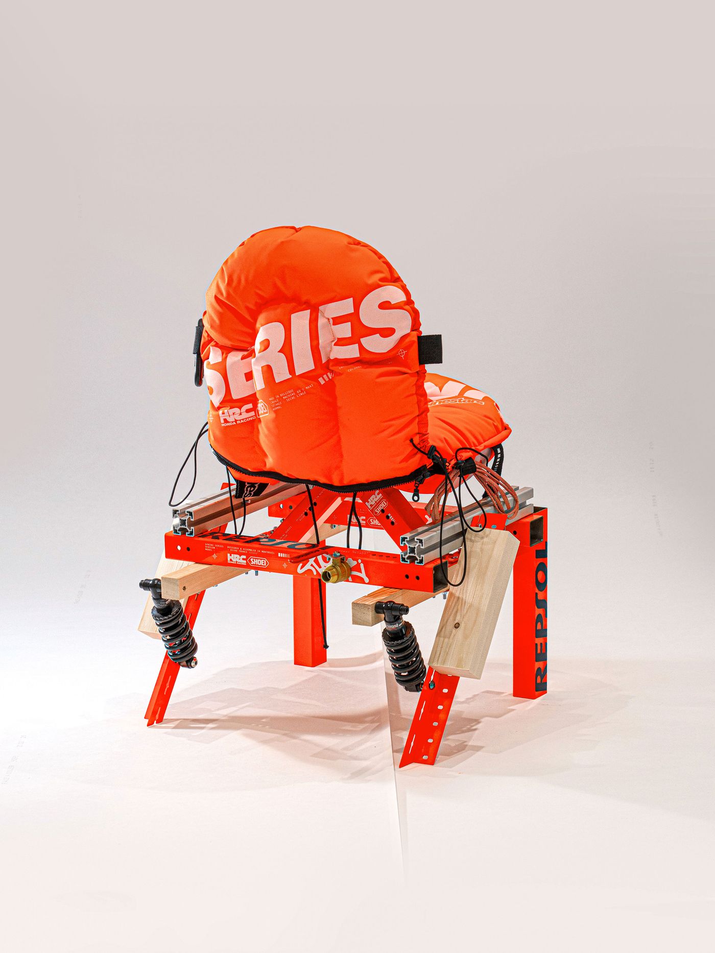 An innovative red structure with a large orange padded seat labeled "SERIES," designed for comfort and stability, featuring springs and wood supports. An innovative red structure with a large orange padded seat labeled "SERIES," designed for comfort and stability, featuring springs and wood supports.