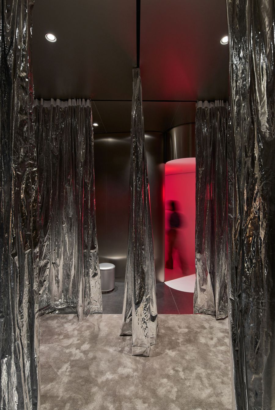 A modern interior featuring metallic curtains, soft beige carpet, and a glowing red alcove, with a silhouette of a person walking through. A modern interior featuring metallic curtains, soft beige carpet, and a glowing red alcove, with a silhouette of a person walking through.